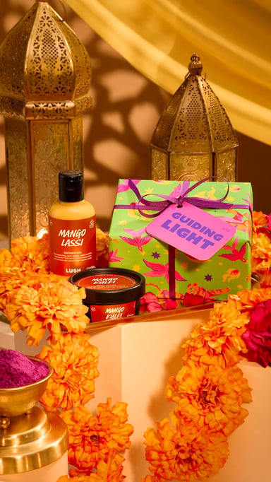 A box, bath bomb, bottle of body wash, candles, and flowers in water