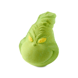 The Grinch. A lime-green Lush bath bomb shaped like a mischievous face, featuring yellow eyes and a smirk, resembling the Christmas character The Grinch.