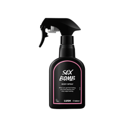 Sex Bomb body spray. A black spray bottle of Lush "Sex Bomb" Body Spray. The product label is black with a dusky pink banded border. White text states the product name and the scent description.