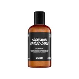 A clear bottle filled with shimmering, bronze-orange Lush Cinnamon Spiced Latte shower gel, topped with a black cap and featuring a black label