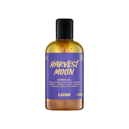 A bottle filled with glossy golden Lush shower gel, featuring a purple label with gold text reading "Harvest Moon".