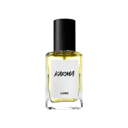 A rectangular glass bottle of Lush 'Karma' perfume with a black cap, filled with light yellow liquid, stands against a solid black background. The white textured label features the name "KARMA" in stylised black lettering.