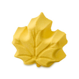 A bright yellow Lush bath bomb shaped like an autumn maple leaf, detailed with embossed leaf veins.