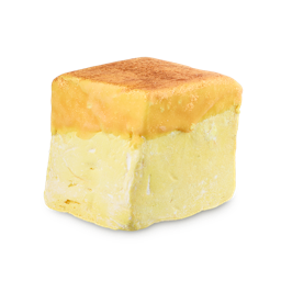 A cube-shaped LUSH Vanilla Delight floating soap. The base is a solid, pale yellow colour, and the top is covered with a golden, sparkling layer sprinkled with a fine lustre.