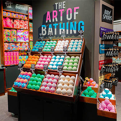 Bathing department. Large display of wall mounted unpackaged brightly coloured bath products. Sign above reads The Art Of Bathing.