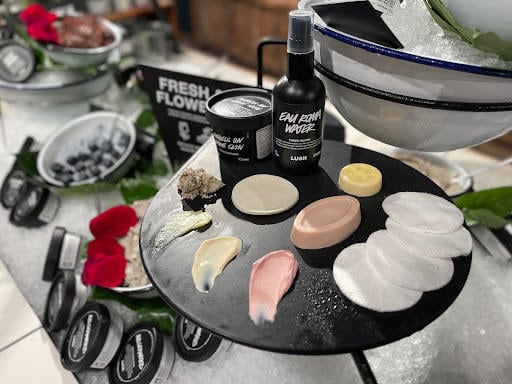 Interior of shop. Large white display unit filled with ice. Bowls and pots of fresh face masks are nestled in the ice. In the foreground is a circular slate with a selection of packaged and unpackaged skincare products.