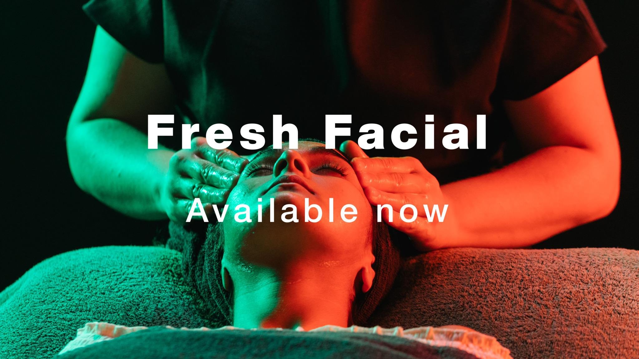 Person having a treatment applied to their face by a therapist. Image is lit from the left with green light and from the right with red light. Text over the top reads Fresh Facial Available Now