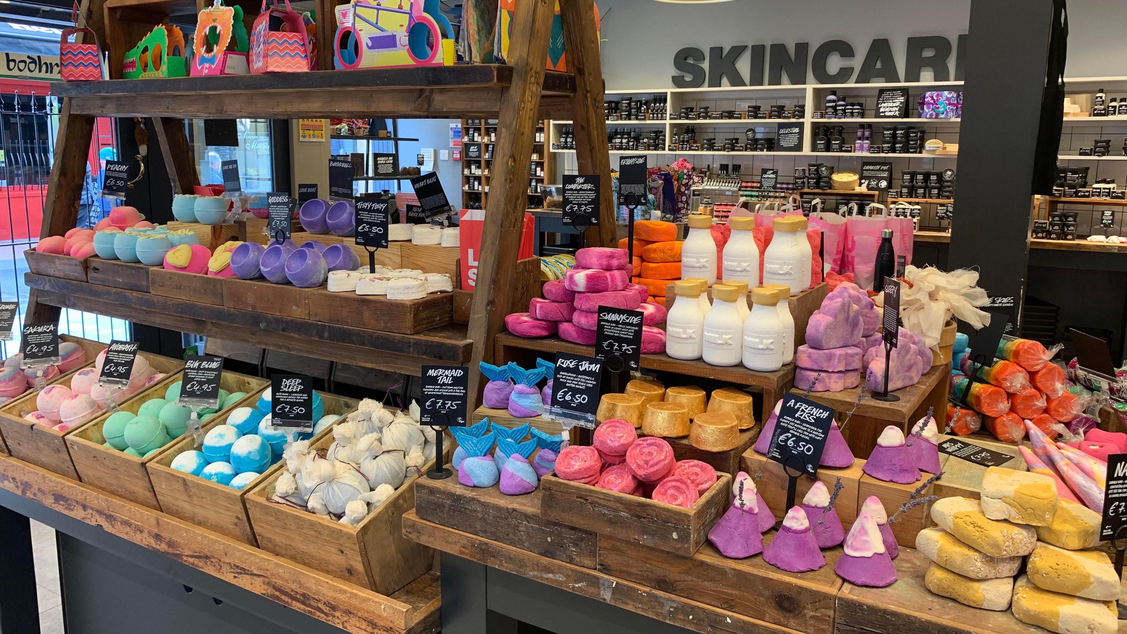 Various unpackaged bath products of various colours and shapes in wooden crates.