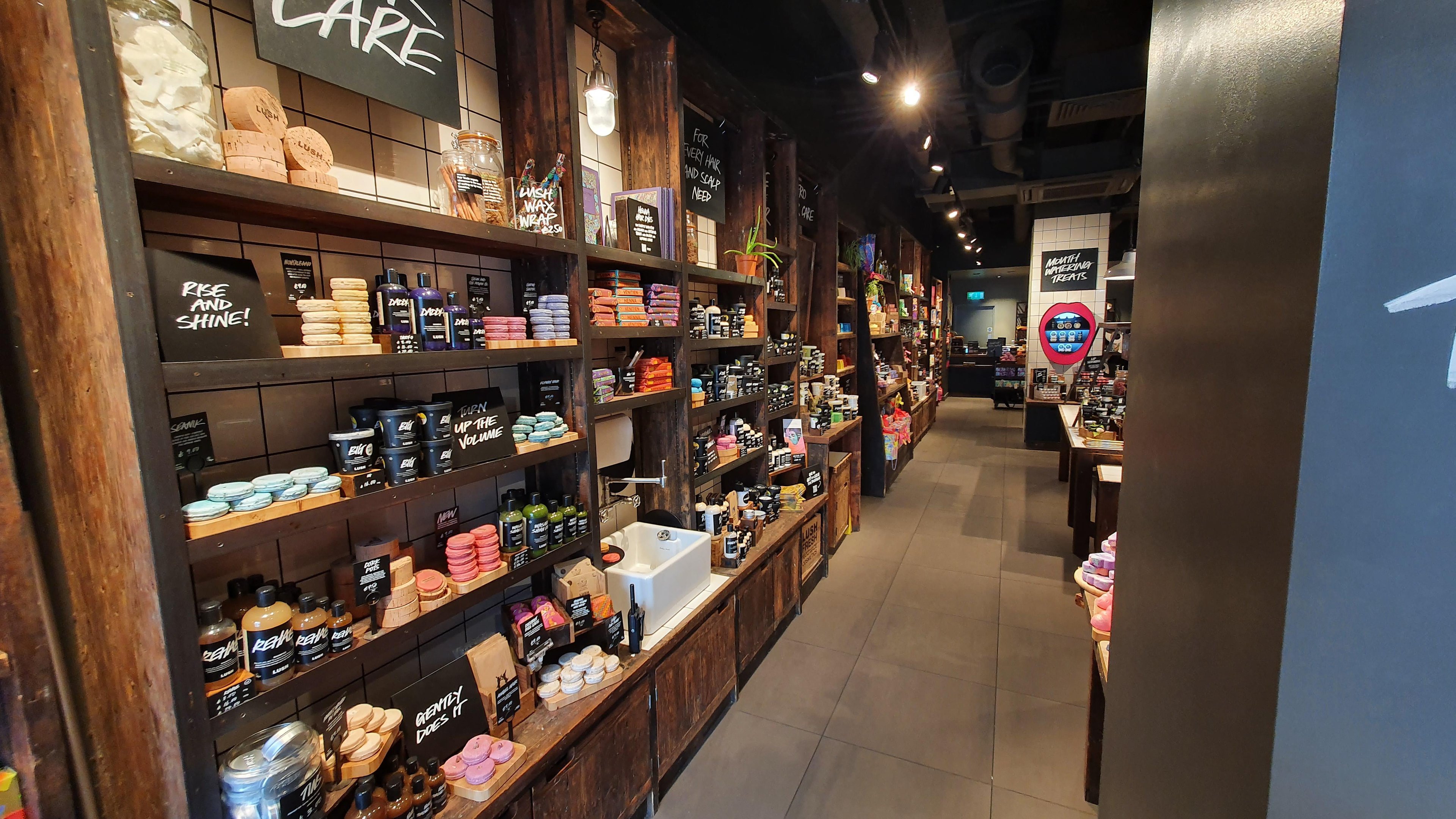 Store Entrance Left, Haircare section. Various packaged and unpackaged products displayed on wooden shelves.