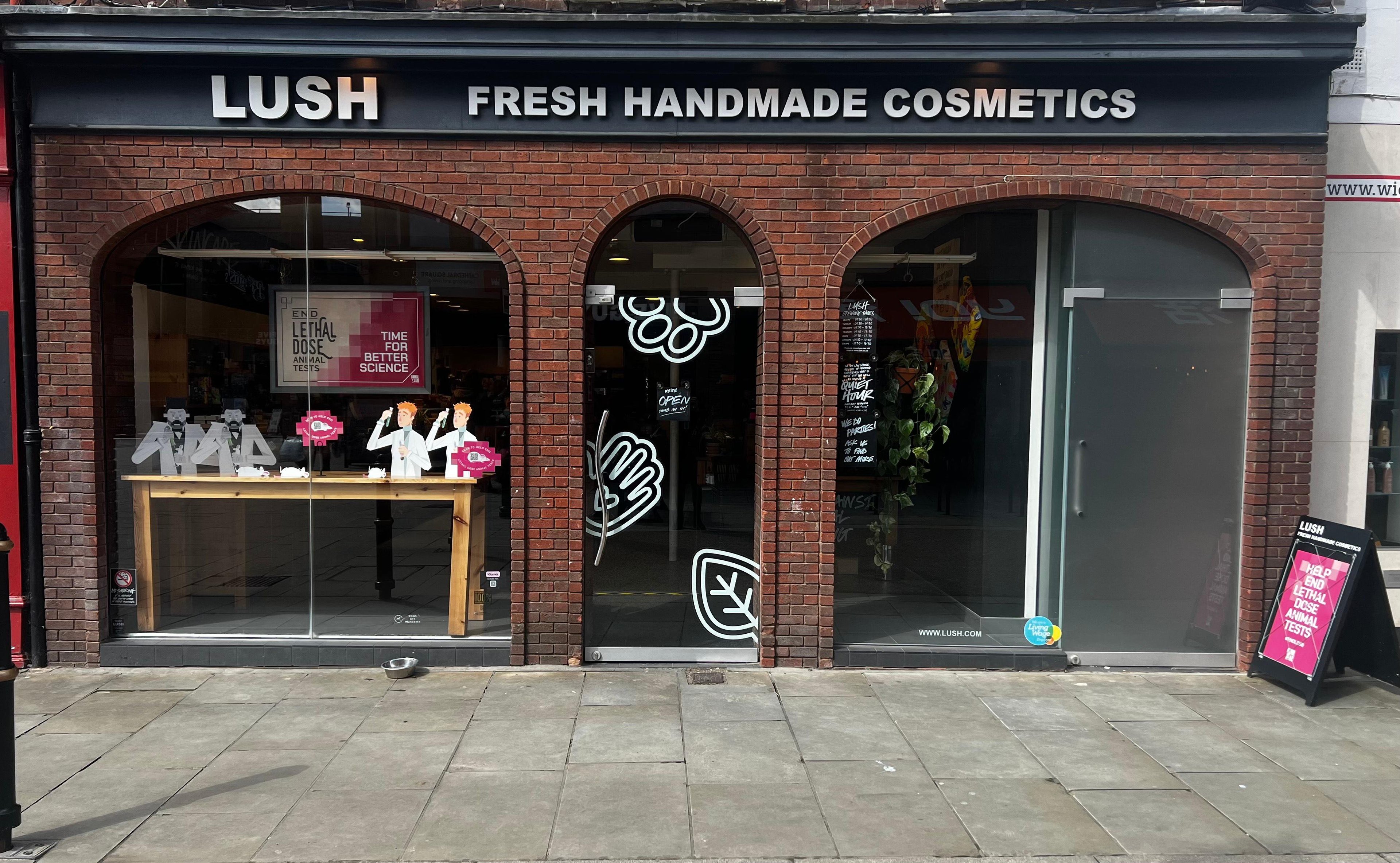 Exterior view of shop. Brick fronted shop, with archways for the windows and doorway. Entrance in centre with  Lush sign above. Products displayed in window to the right side of entrance.