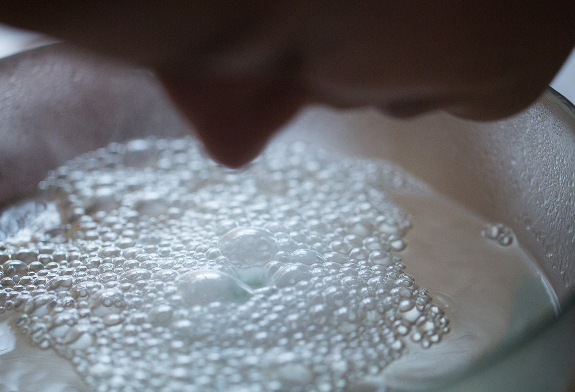 The silhouette of a person's face can be seen hovering above a bubbling, steaming bowl of water.