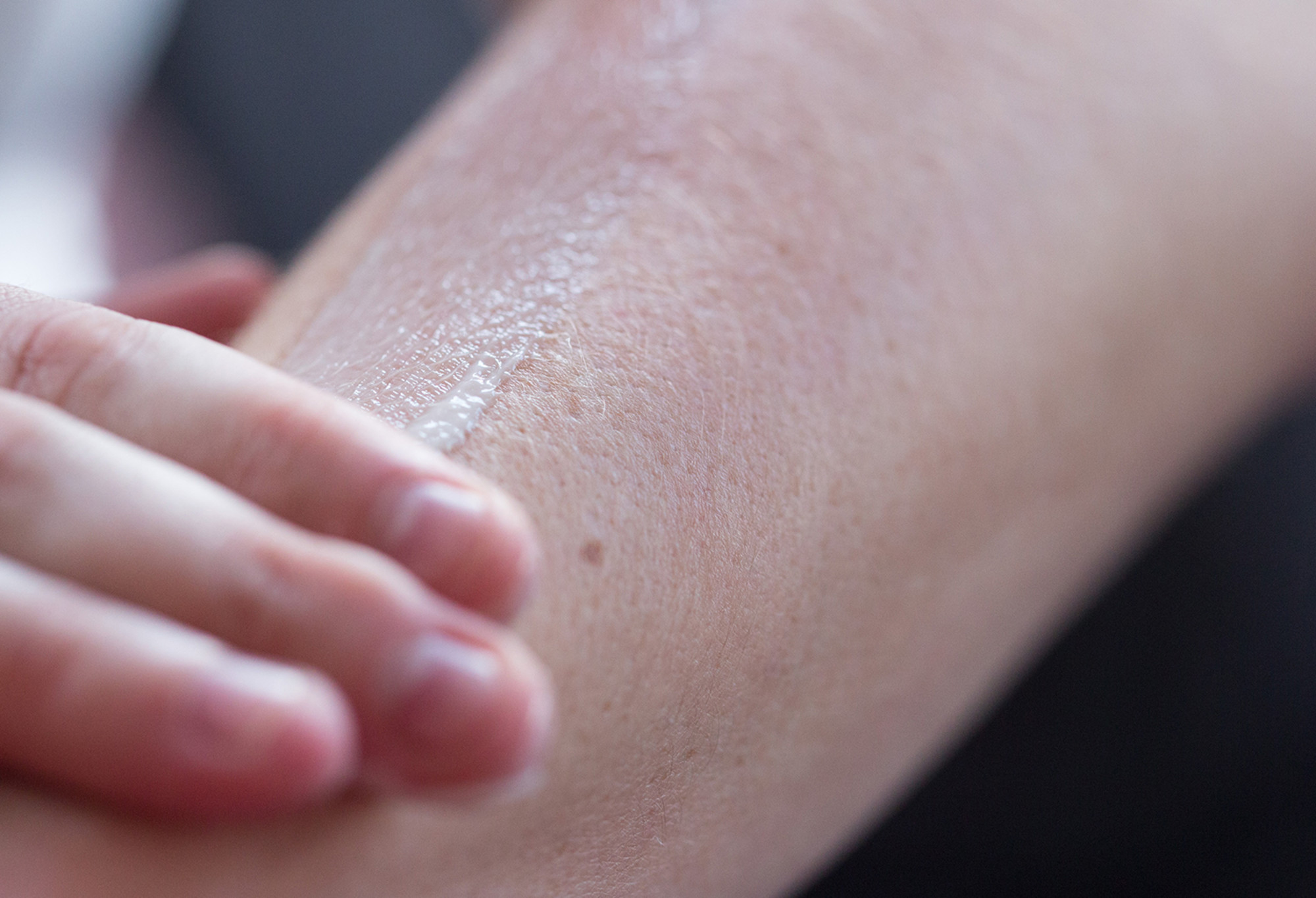 A thin layer of Charity Pot, a cream coloured body lotion, is rubbed into an arm.