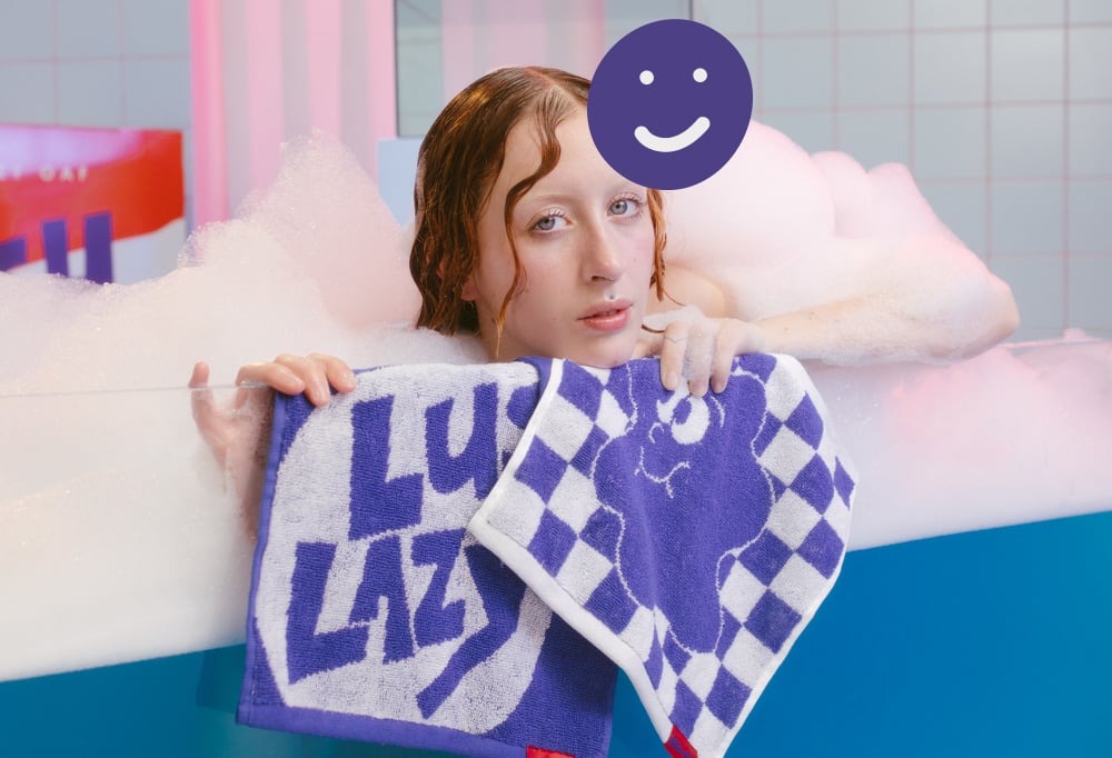 A model displays the Lush x Lazy face cloths from a very bubby bath tub.