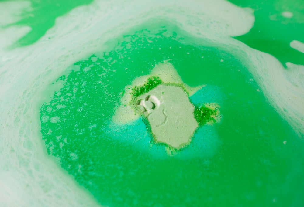 Wash Buddys' smiling face is only just visible as the bath bomb melts and fizzes away into pastel light and dark green waters.