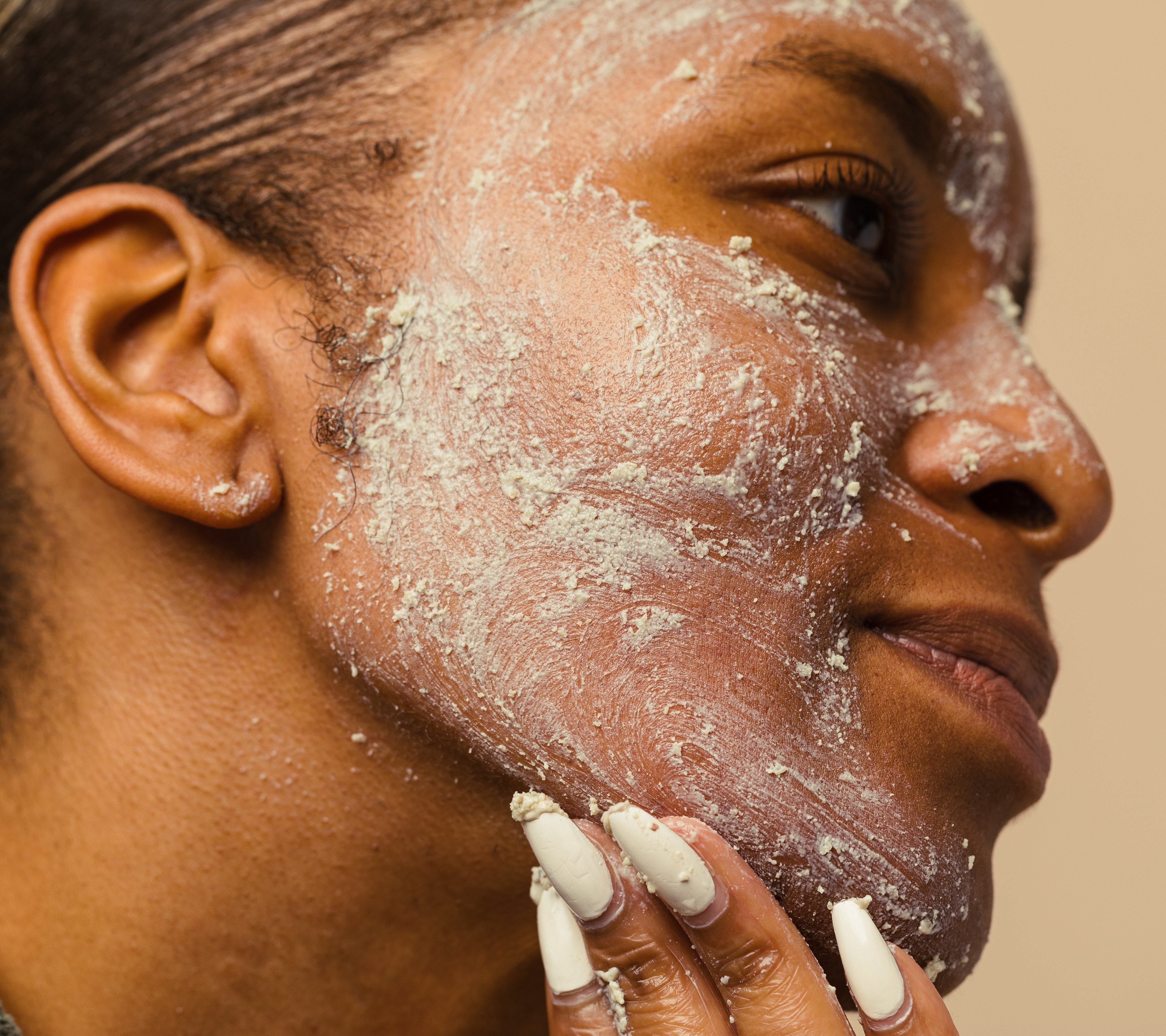 A face is seen side on, cheek being cupped, covered in Angels on Bare Skin, a cream-coloured, textured fresh cleanser.