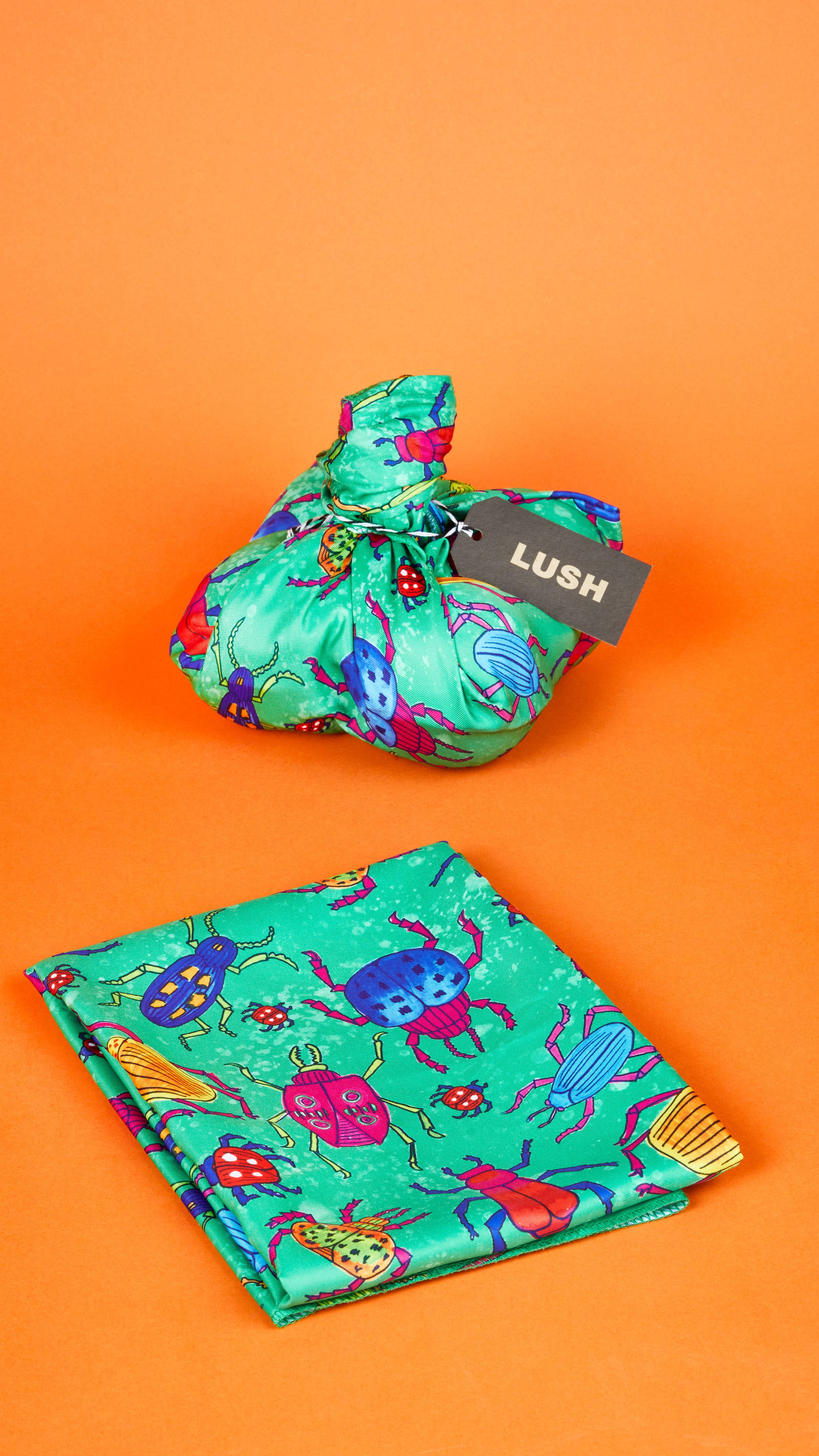 Bugs Knot Wrap displayed two different ways, folded and holding a gift, in front of a bright orange background.