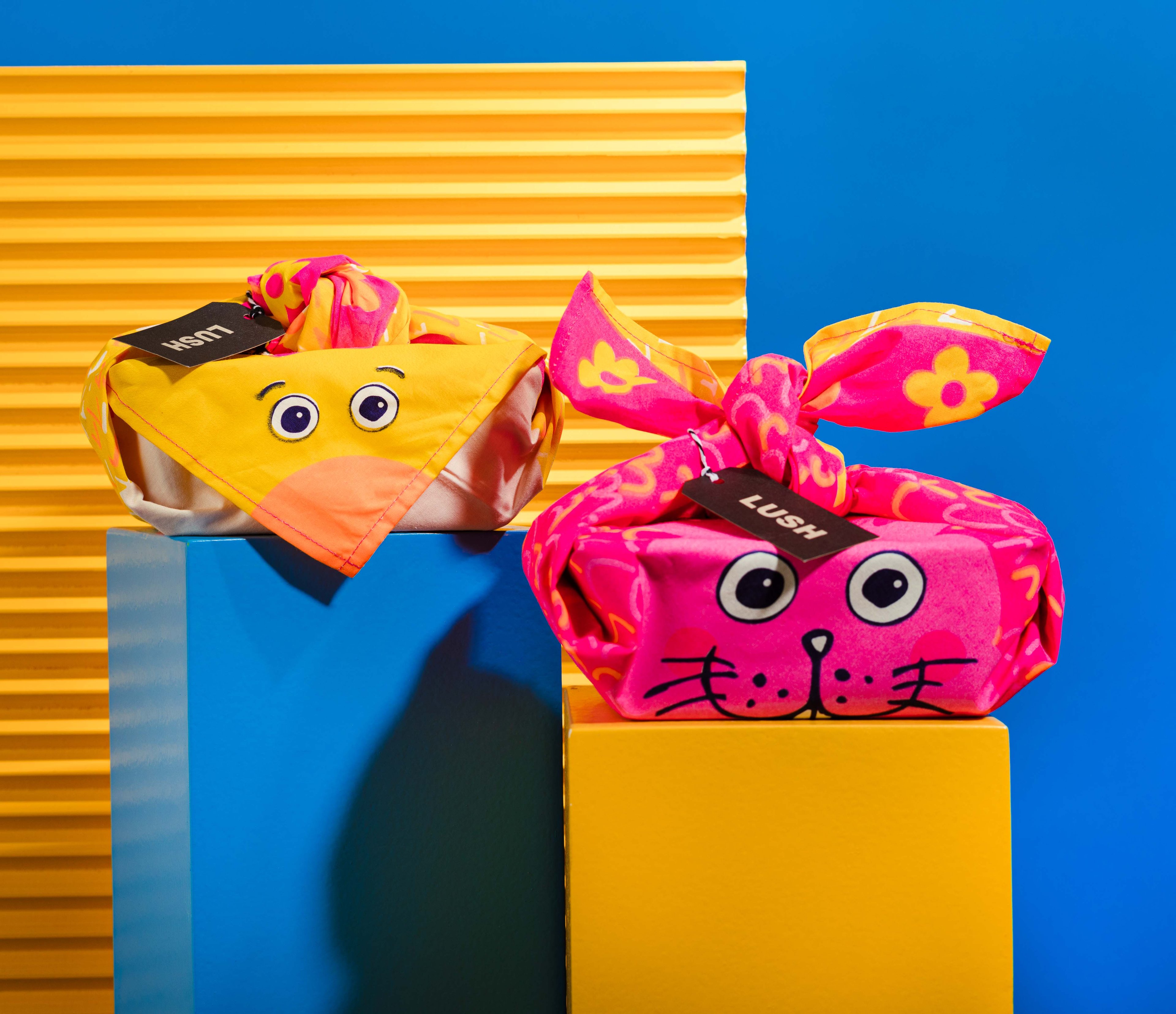 The Knot Wrap is shown wrapped, one with the bird face, the other with a rabbit face. In front of yellow and blue background.