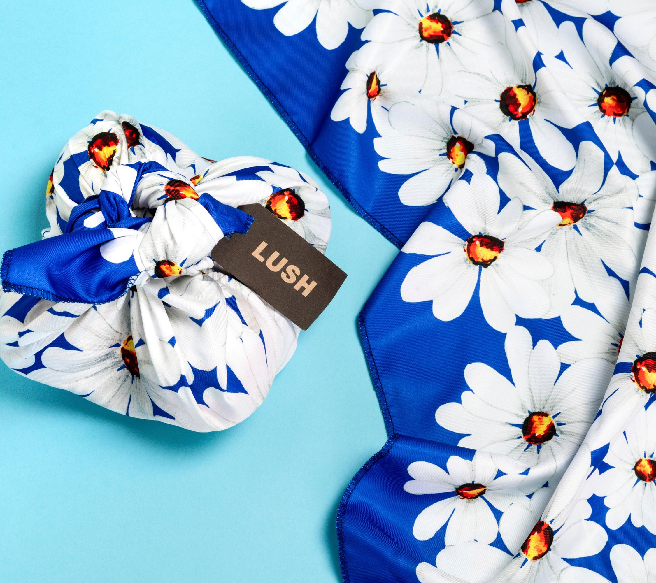 The knot wrap is wrapped and knotted around a 4 bath bombs, as well as laid out flat, on a bright blue background.