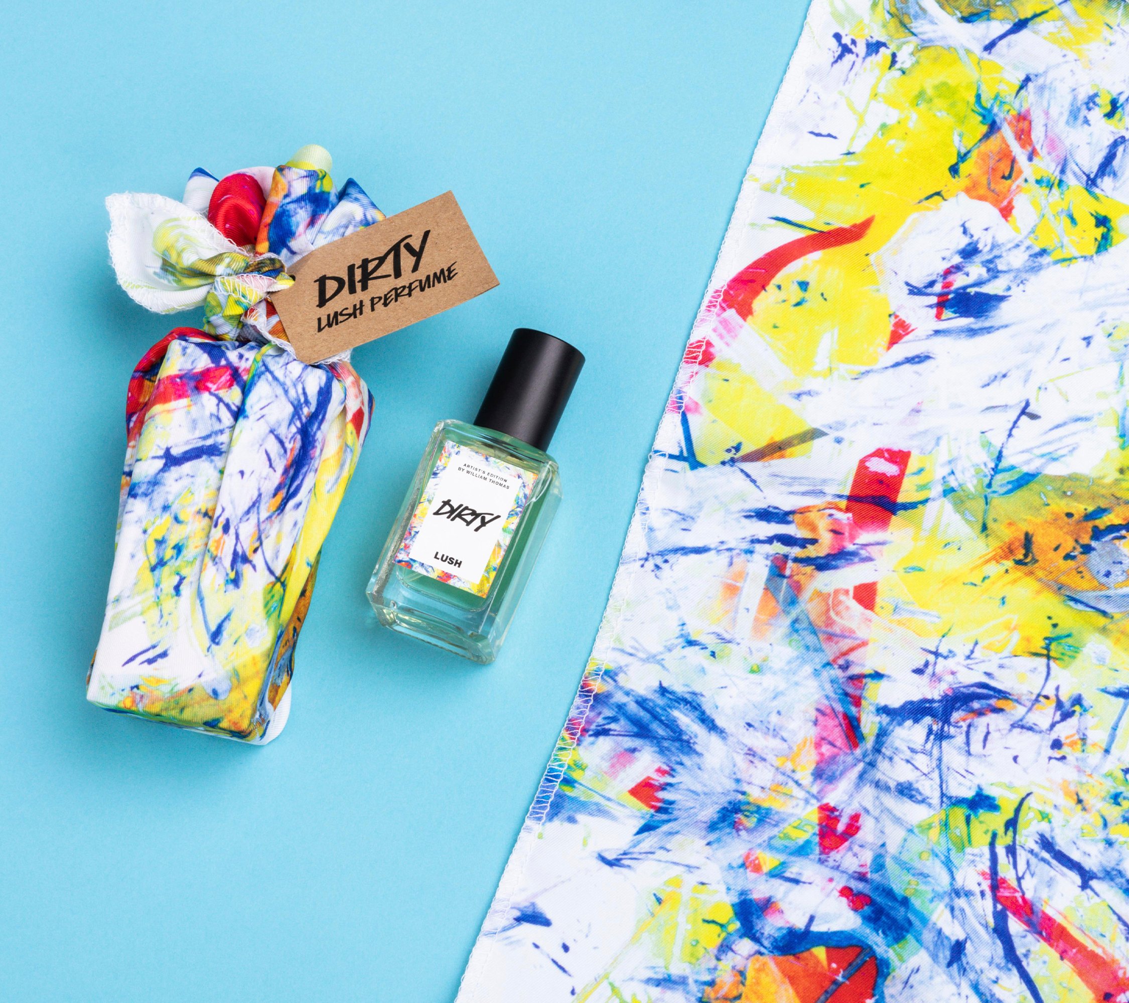 Dirty lies on a light blue background, alongside its two elements: a small bottle of Dirty perfume and a colourful knot wrap.