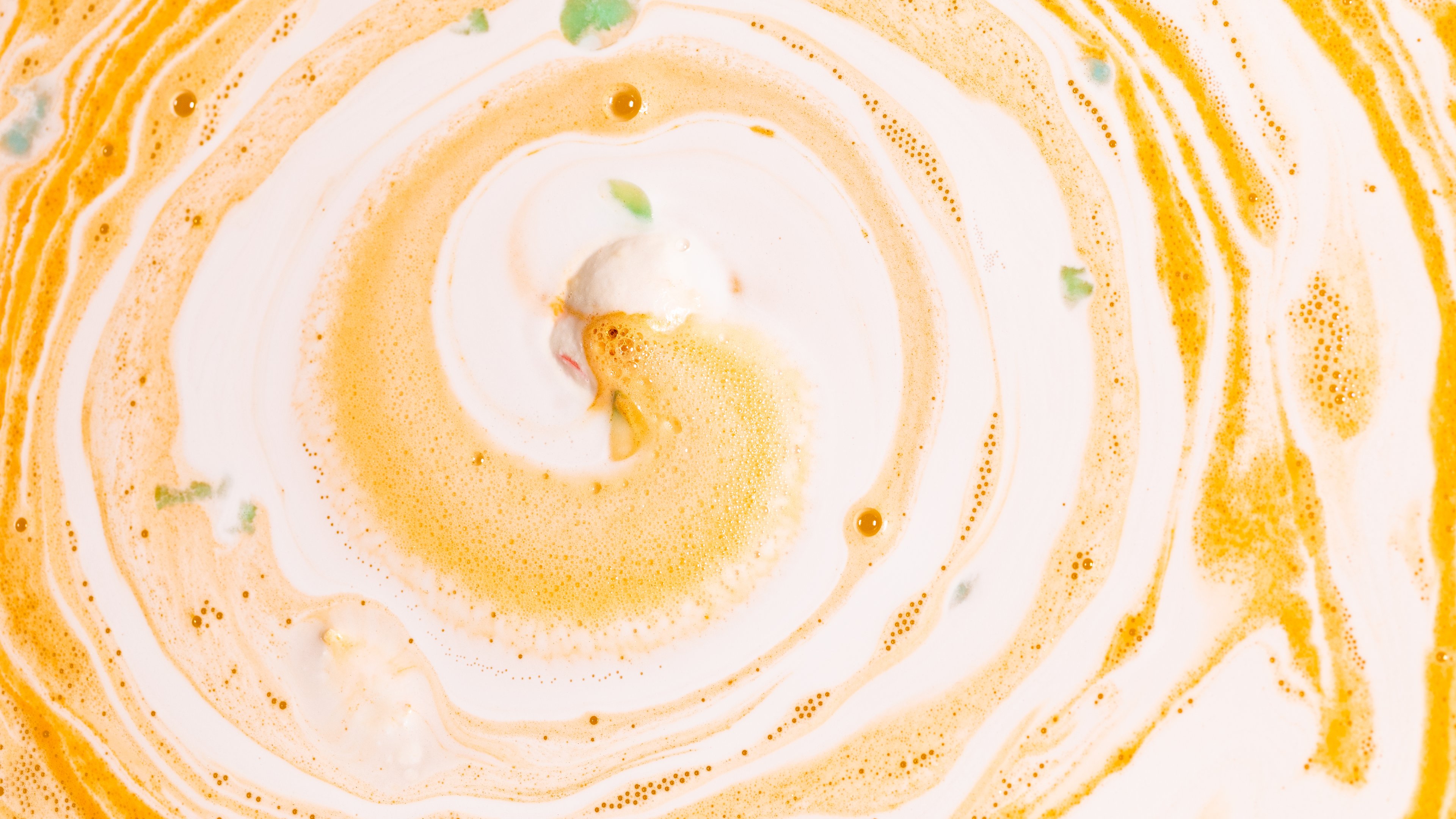 Dragon's Egg Bath bomb sits fizzling in a refreshing swirl of orange and white, with hints of green.