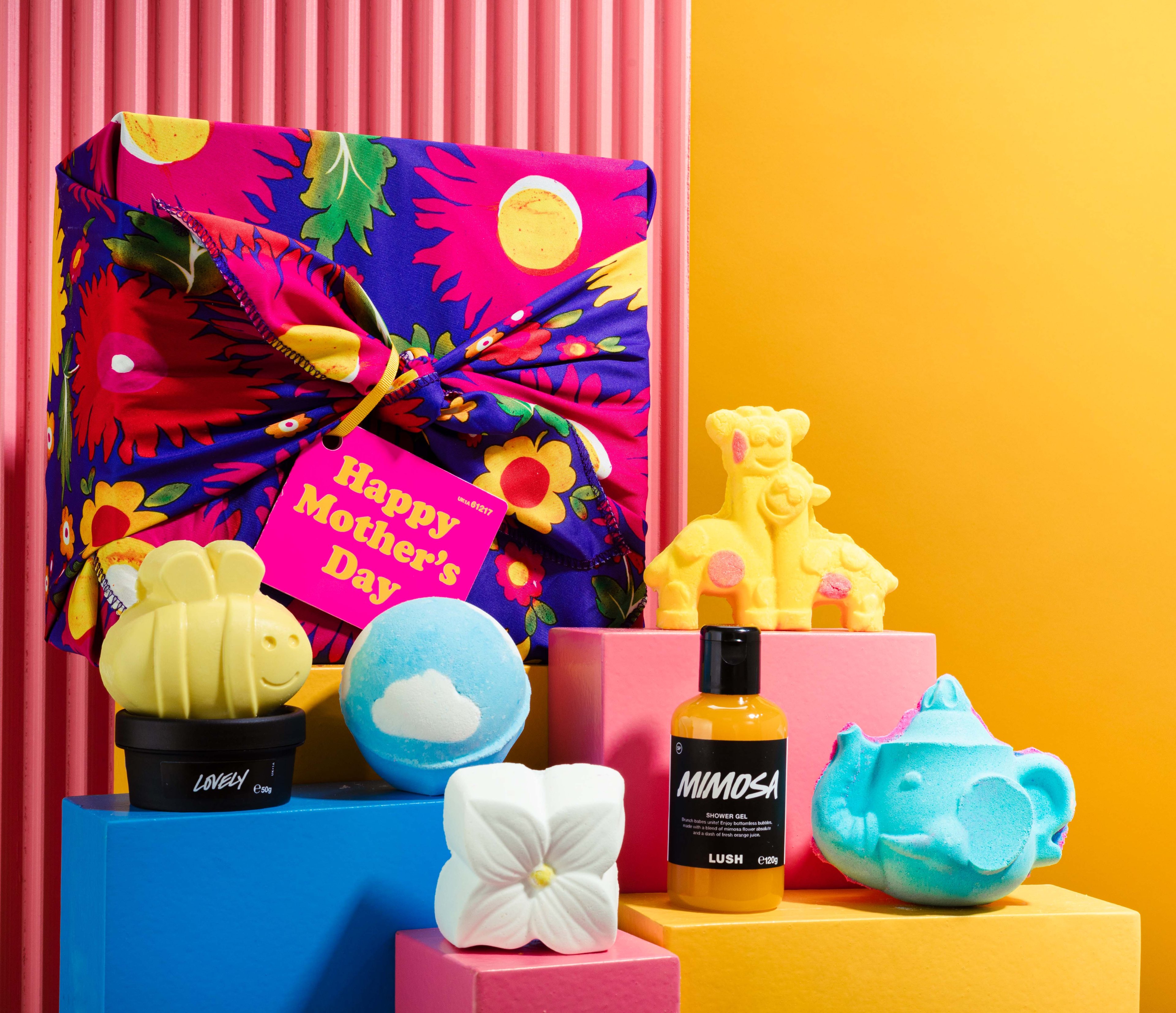 The gift sits face up on a soft pink background, surrounded by its product contents lying flat. 