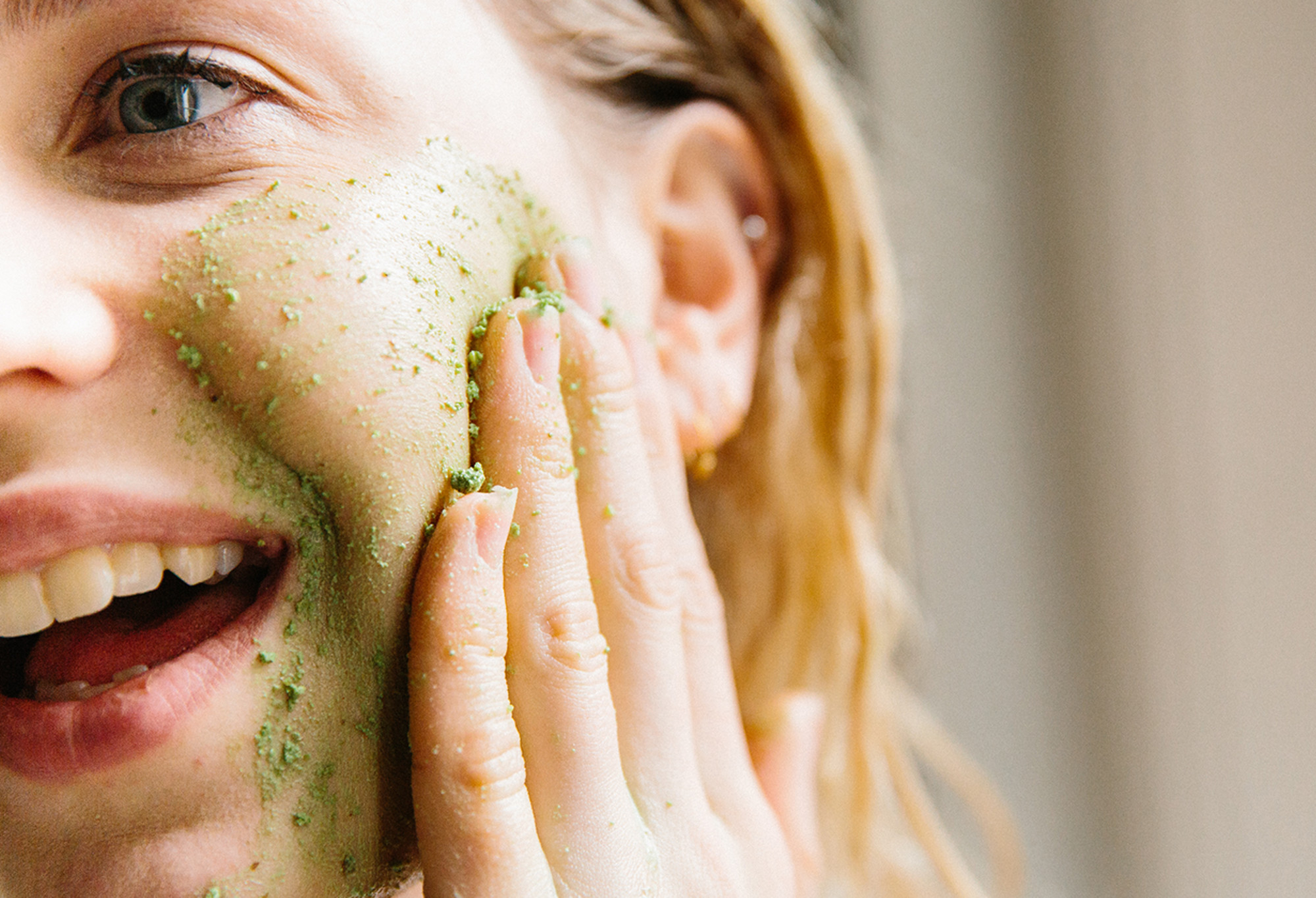 A smiling face massages Herbalism - a vibrant green, textured, fresh cleanser, made into a paste - into their cheeks.
