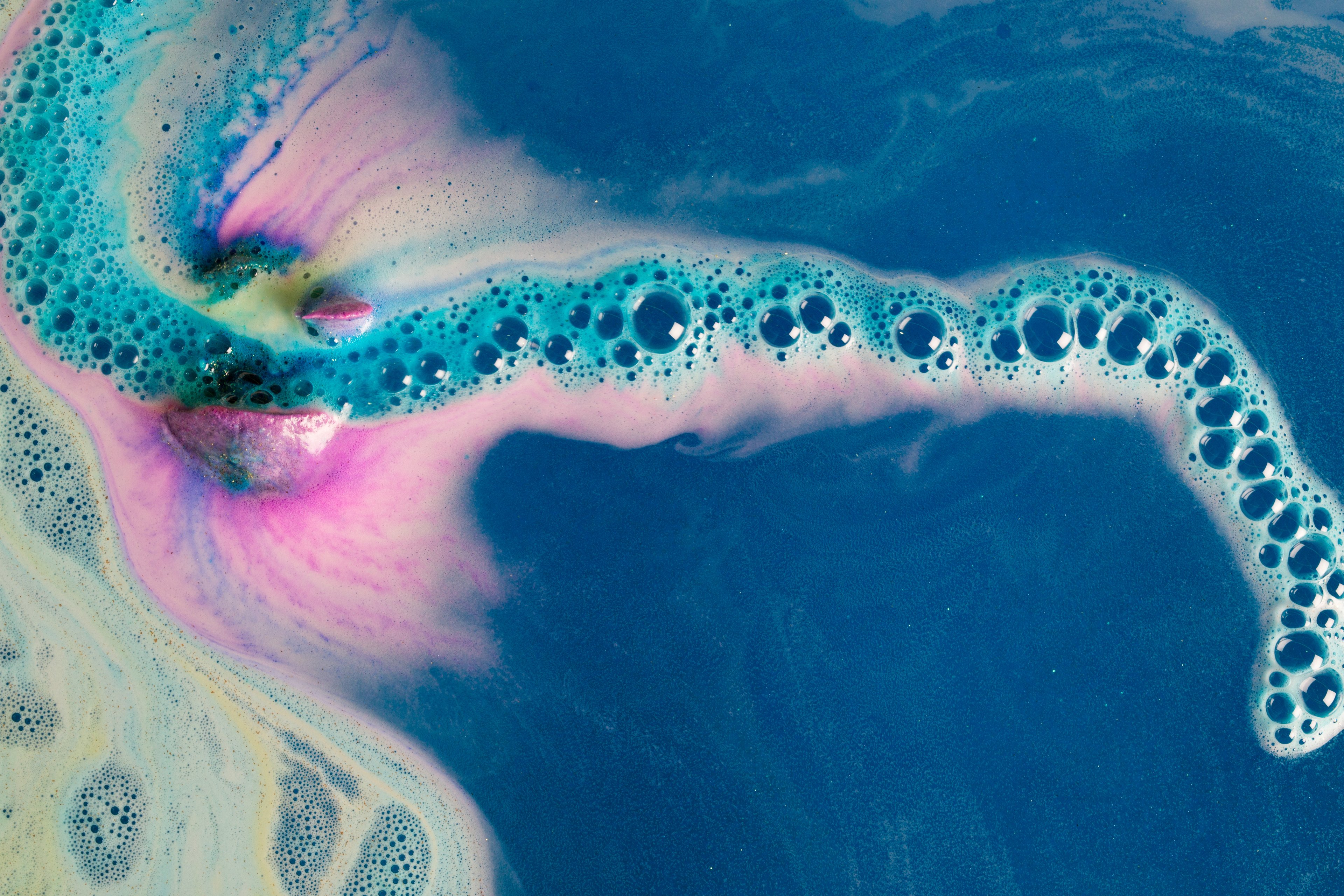 The Intergalactic bath bomb slowly fizzing, creating a solar system of bubbles with pink and blue swirls and hints of yellow.