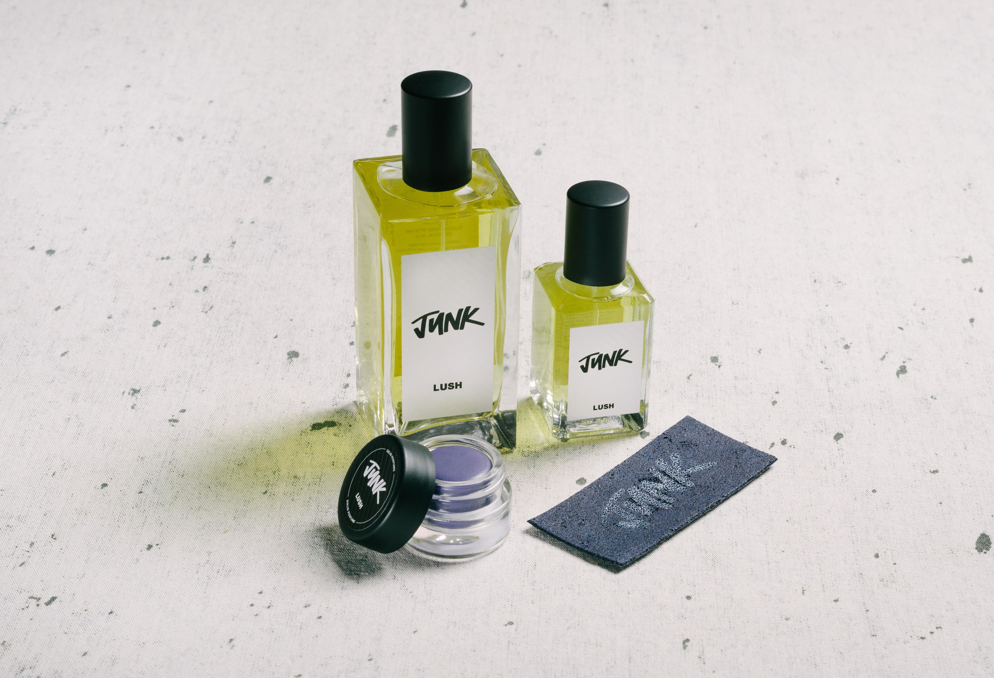 The whole Junk fragrance collection is displayed on a white surface, flecked with grey.