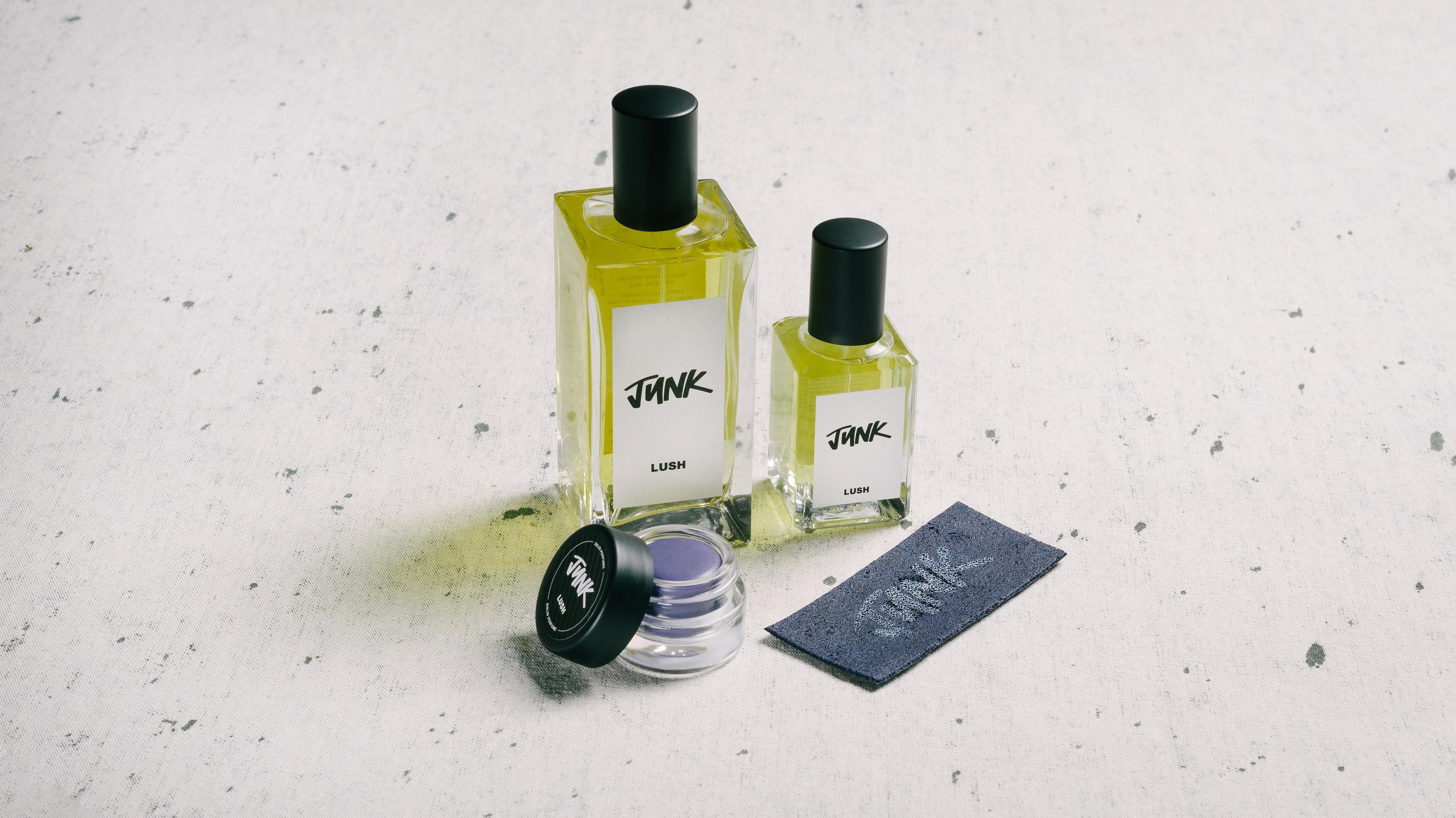 The whole Junk fragrance collection is displayed on a white surface, flecked with grey.
