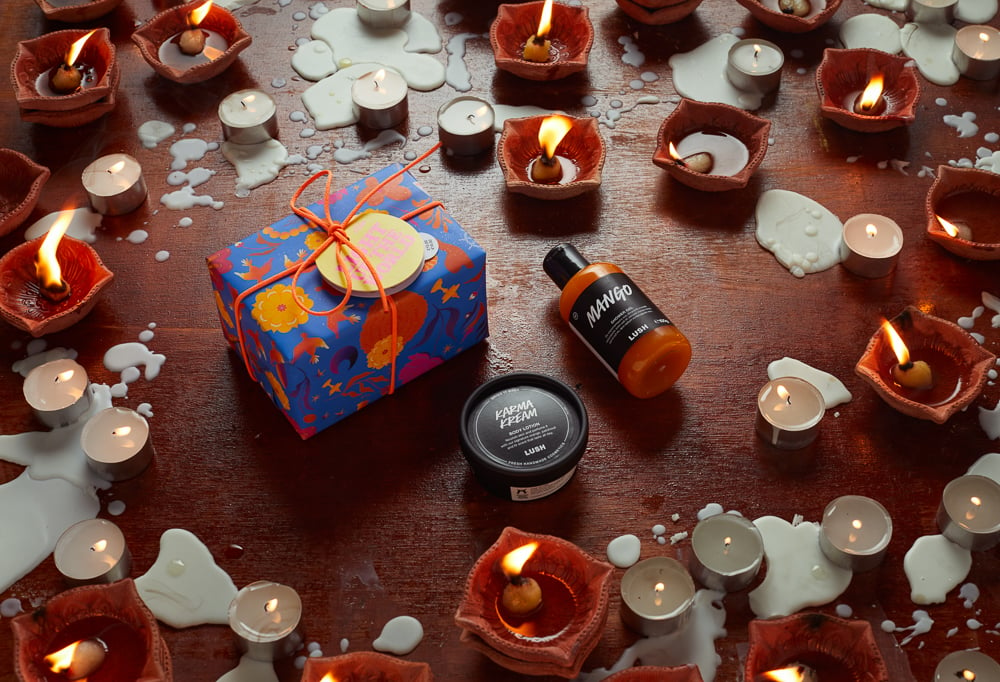 The gift is on a wooden surface, surrounded by its product contents and lit tealight candles.