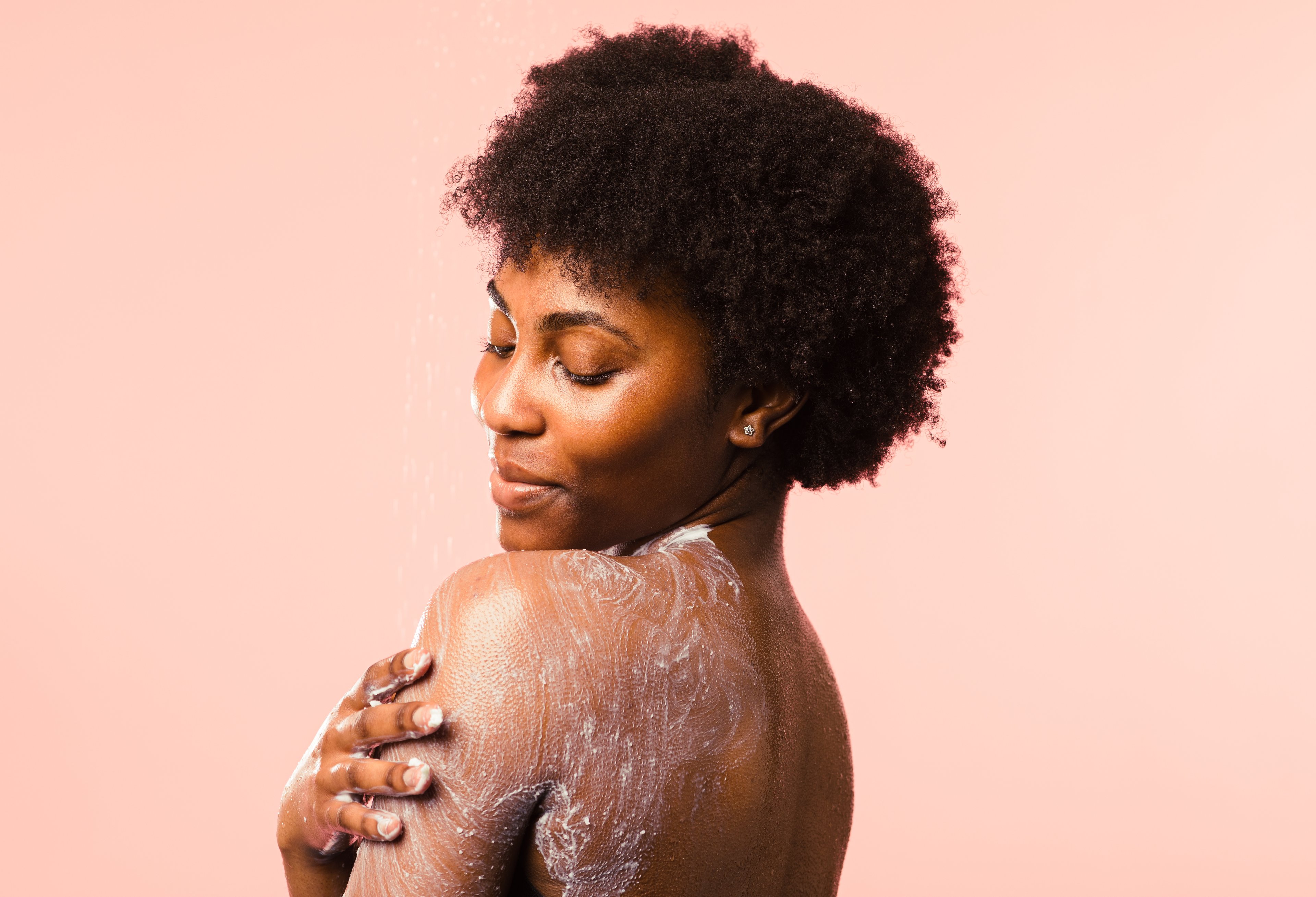 A person stands with at an angle to show the white Ocean Salt exfoliator rubbed on their shoulder and back