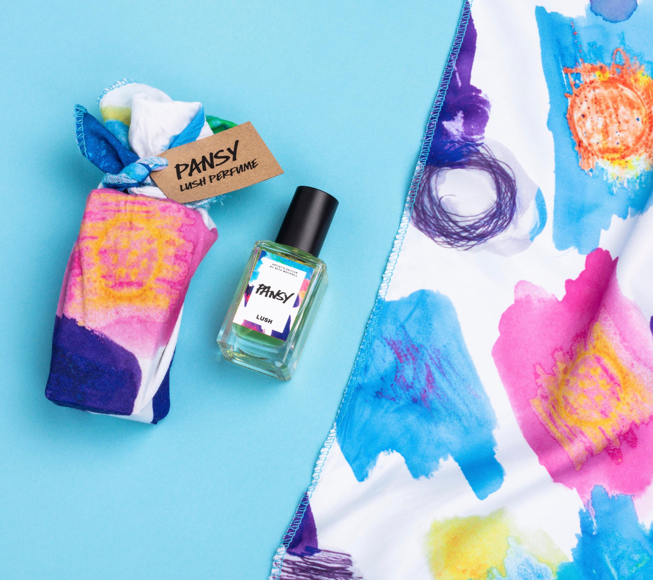 Pansy lies on a light blue background, alongside its two elements: a small bottle of Pansy perfume and a colourful knot wrap.