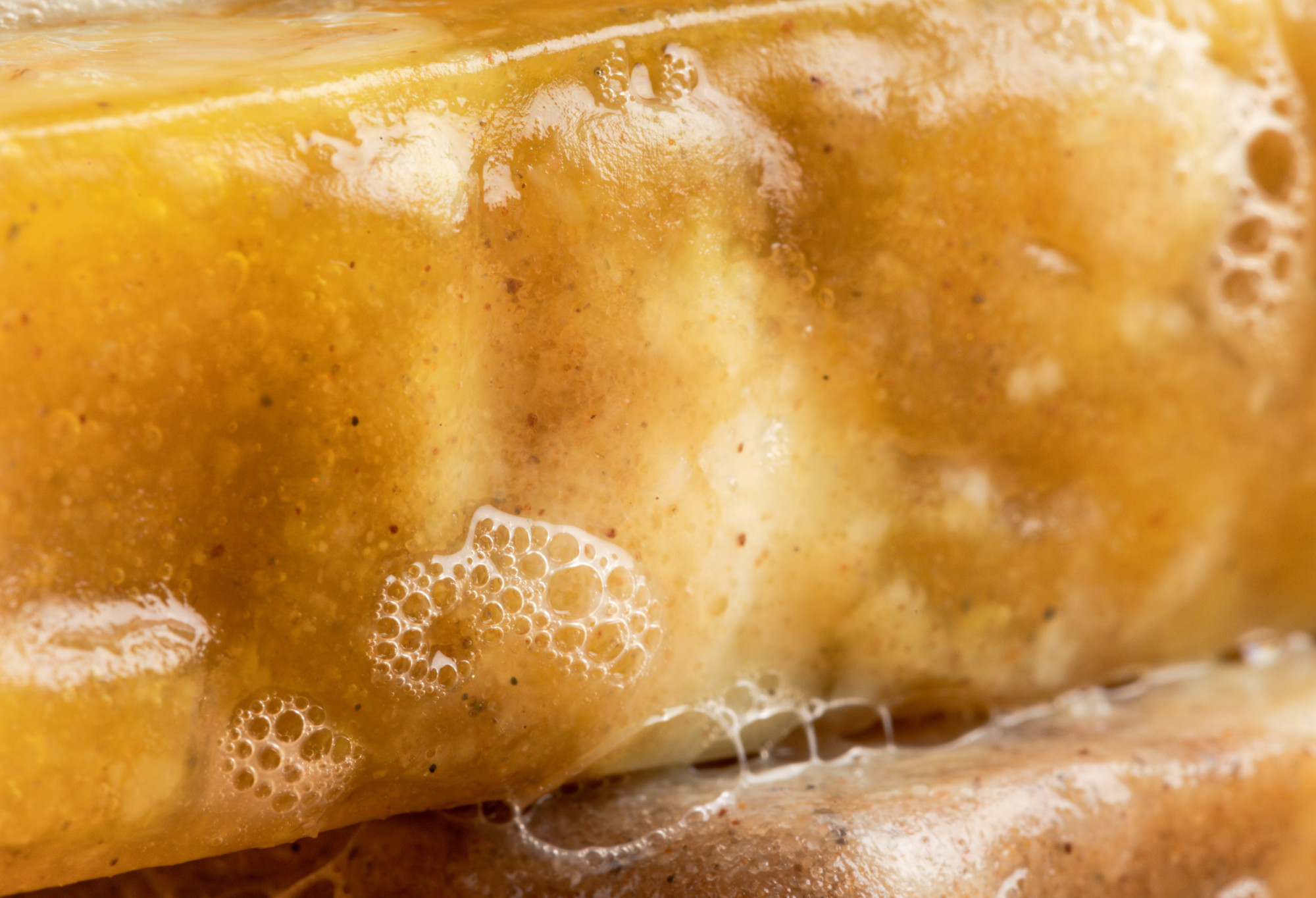 A bubbly close-up of Sandstone: a sandy yellow coloured soap, with a roughly textured surface created by sand.