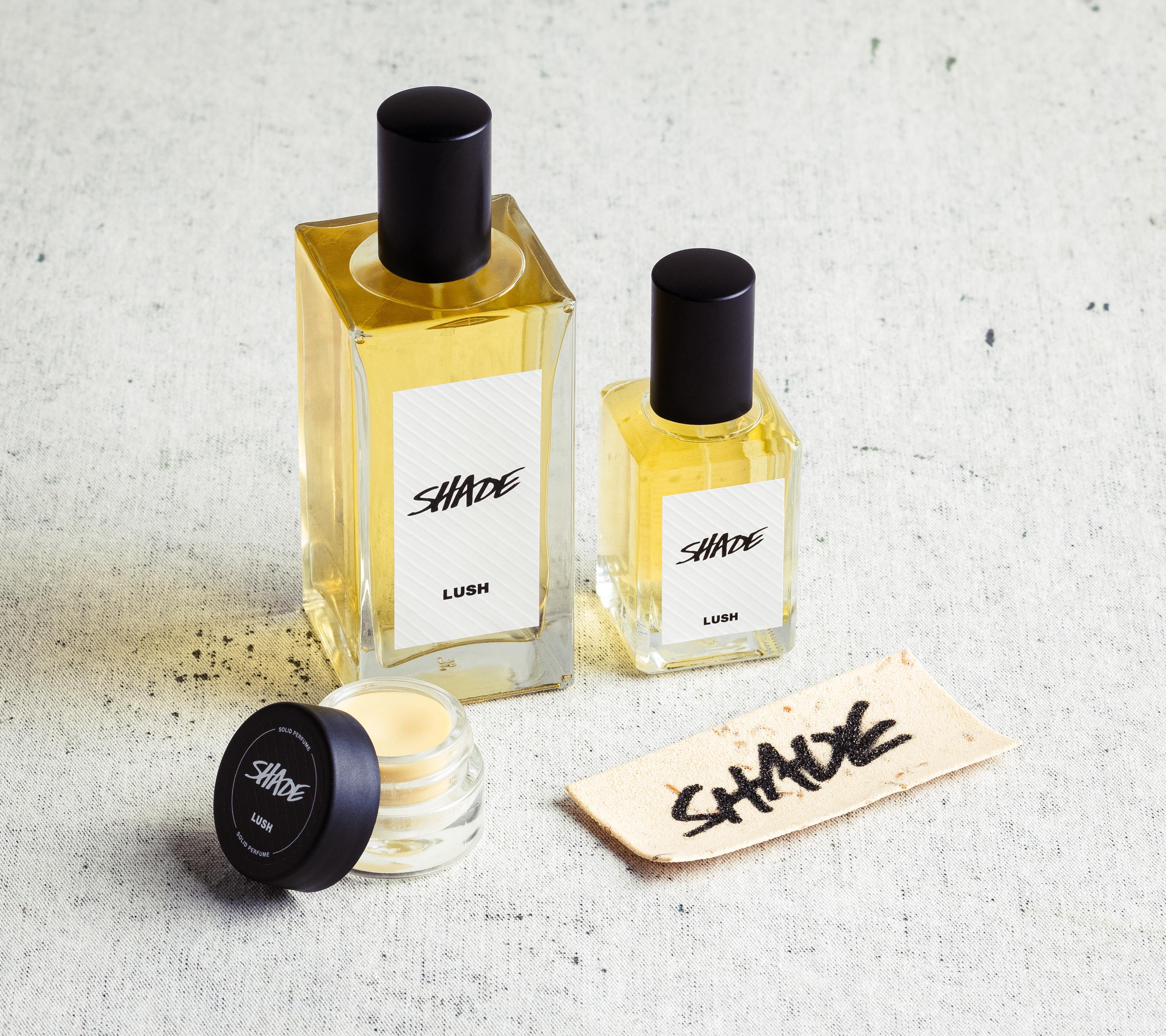 The whole Shade fragrance collection is displayed on a white surface, flecked with grey.