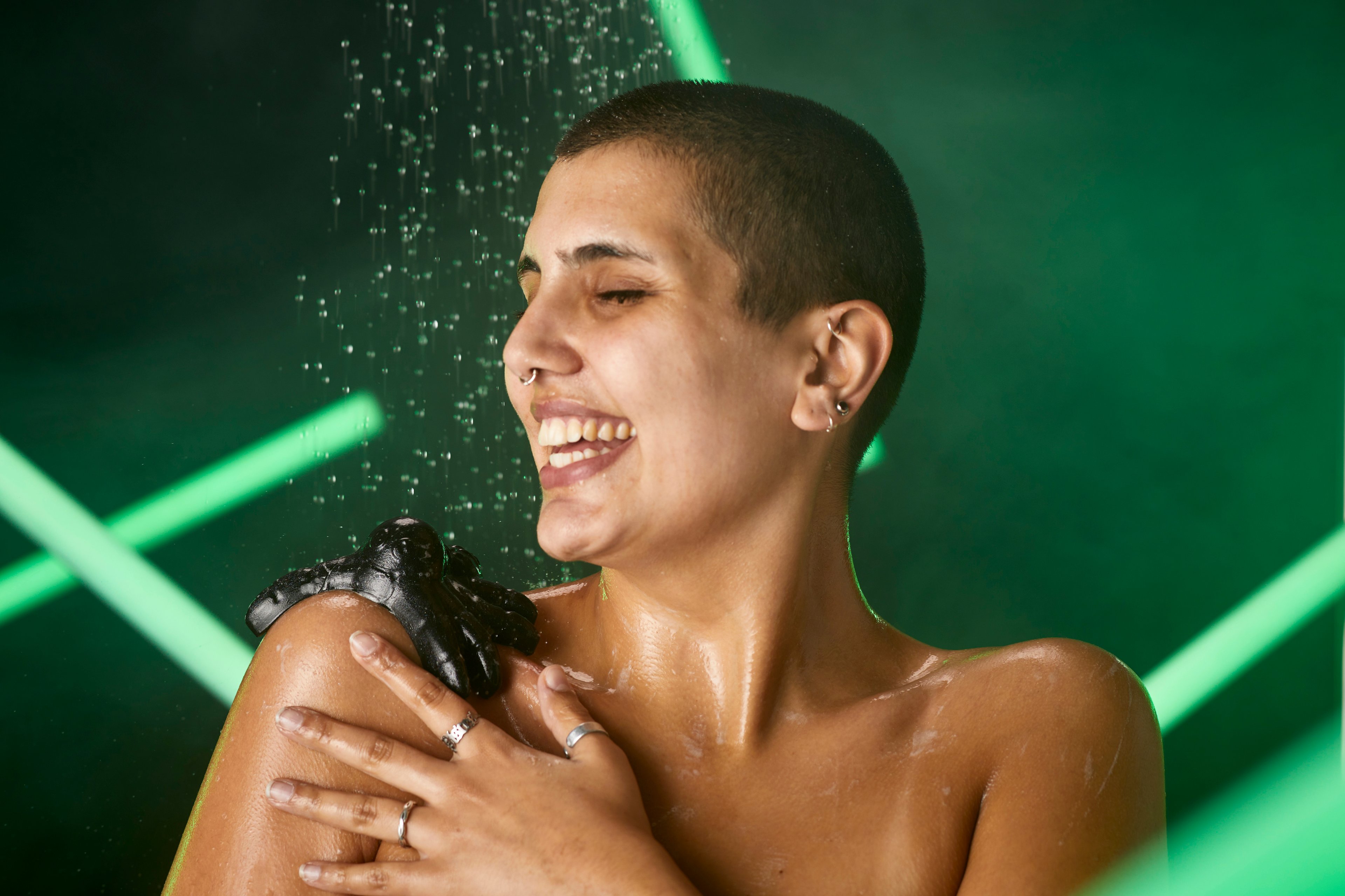 A model smiles in the shower as they balance the Tarantula shower jelly on their shoulder. 