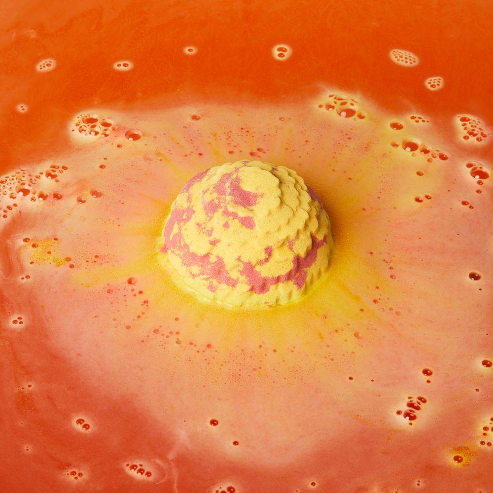 The Cempasúchil bath bomb is slowly fizzing away in bath water producing a sea of deep orange with soft foam.