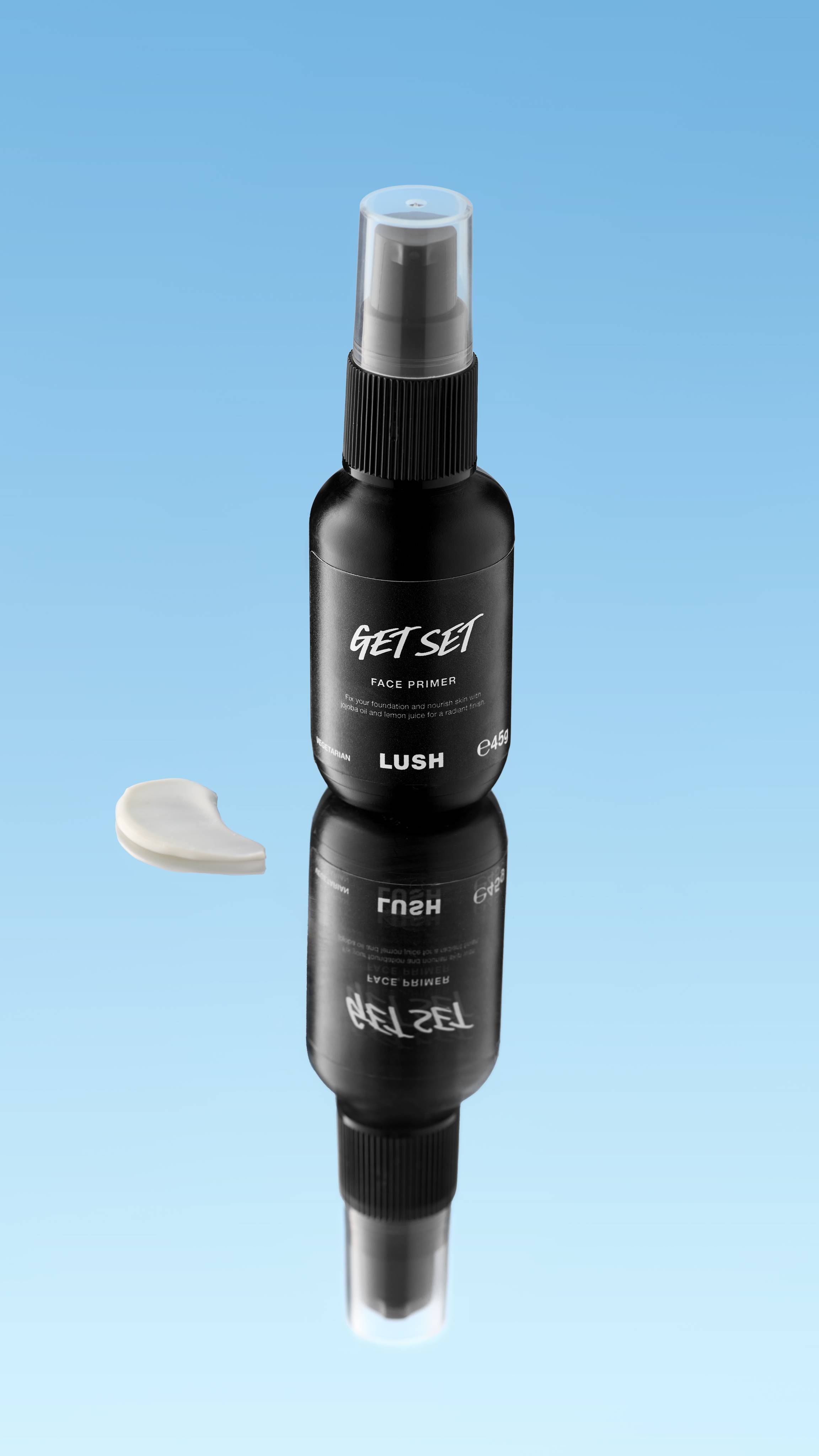 A close-up product swatch of a thick, elongated, textured streak of set primer. The product has a creamy, smooth texture and a pale, off-white color