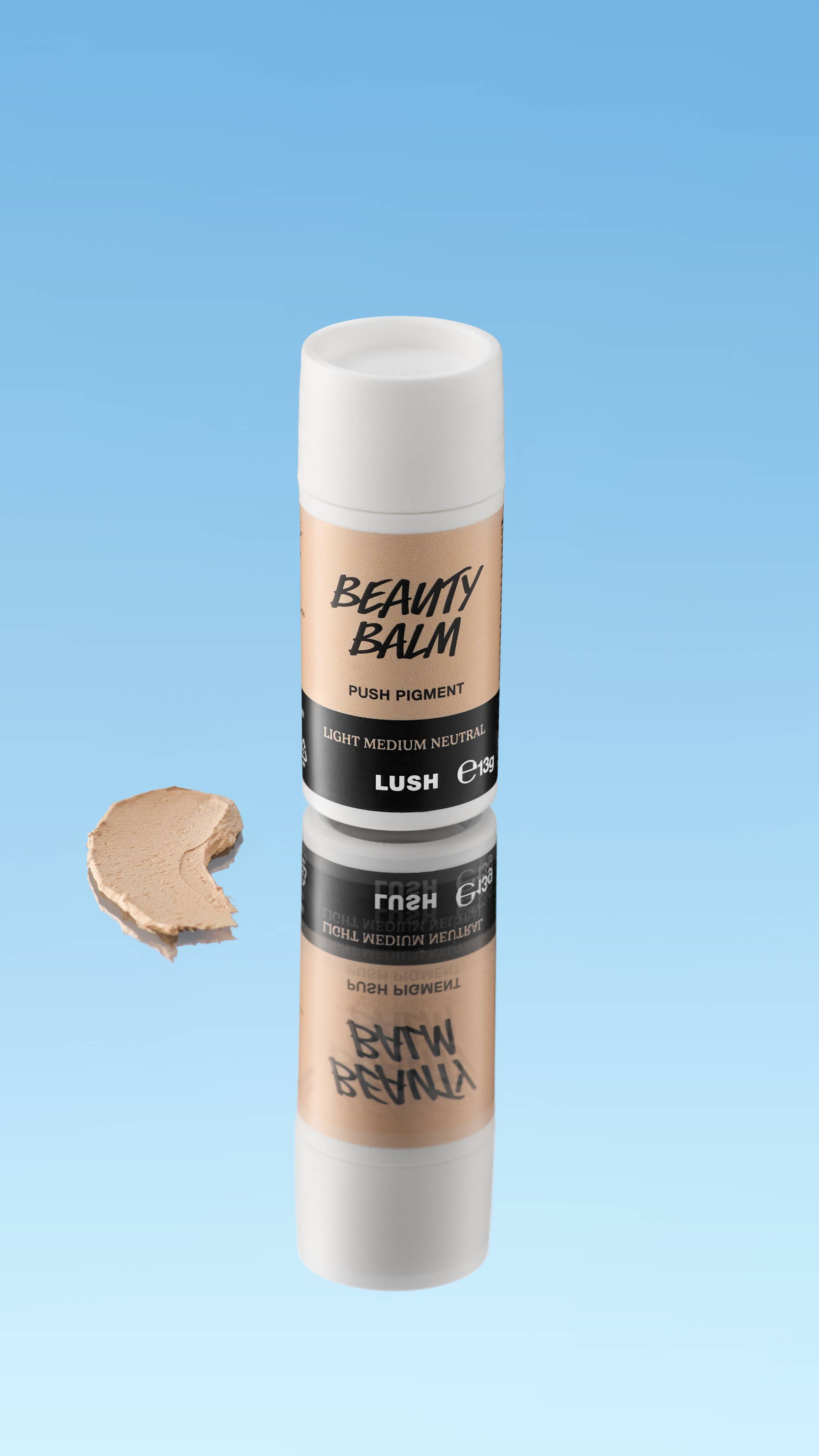 A close-up product swatch of a thick, elongated, textured streak of Light Medium Neutral Beauty Balm. The color is a neutral light medium beige/tan
