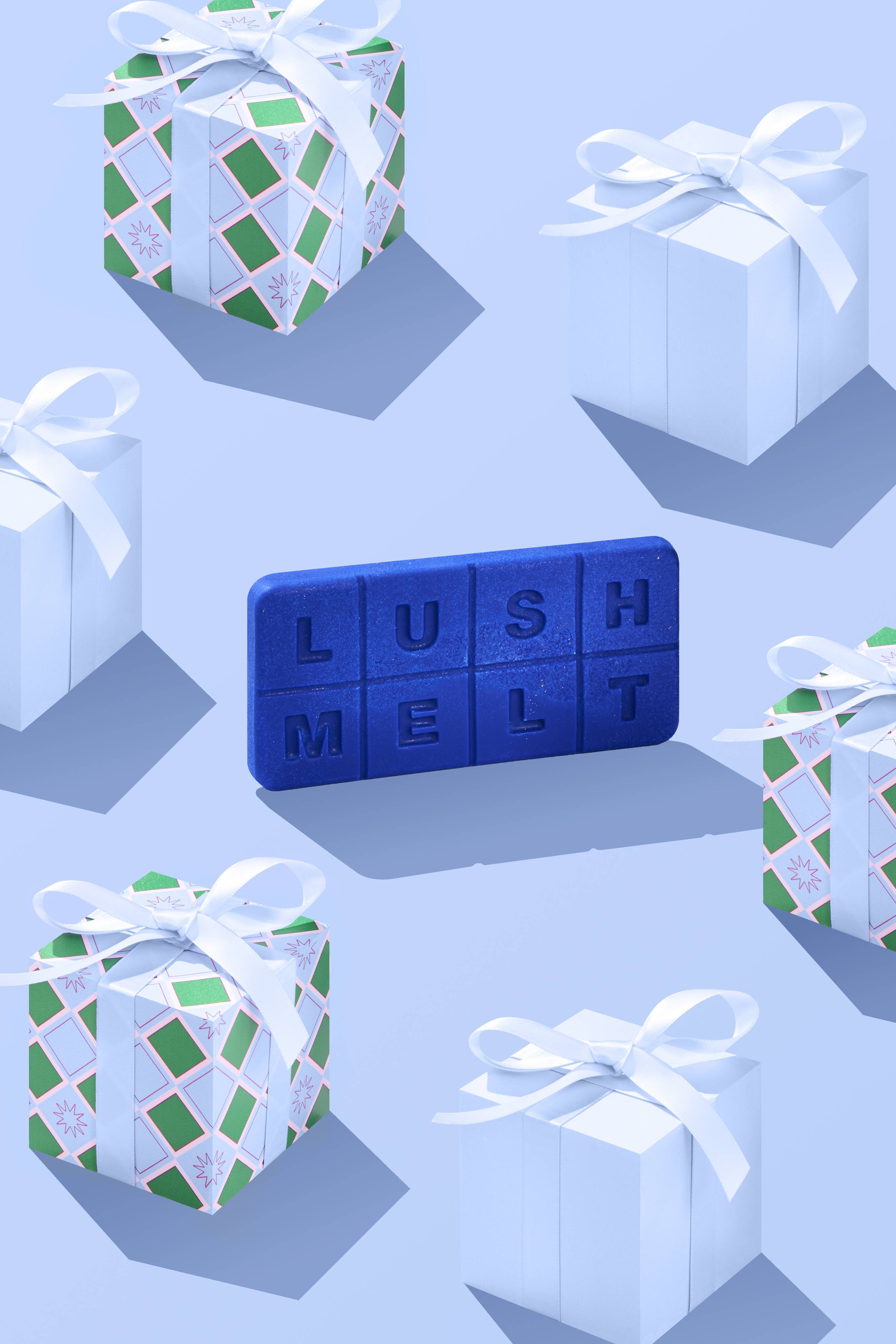 The image shows the rectangular, electric-blue Shoot For The Stars LUSH melt standing at an angle on a pale blue background. Wrapped gifts sit around the melt.