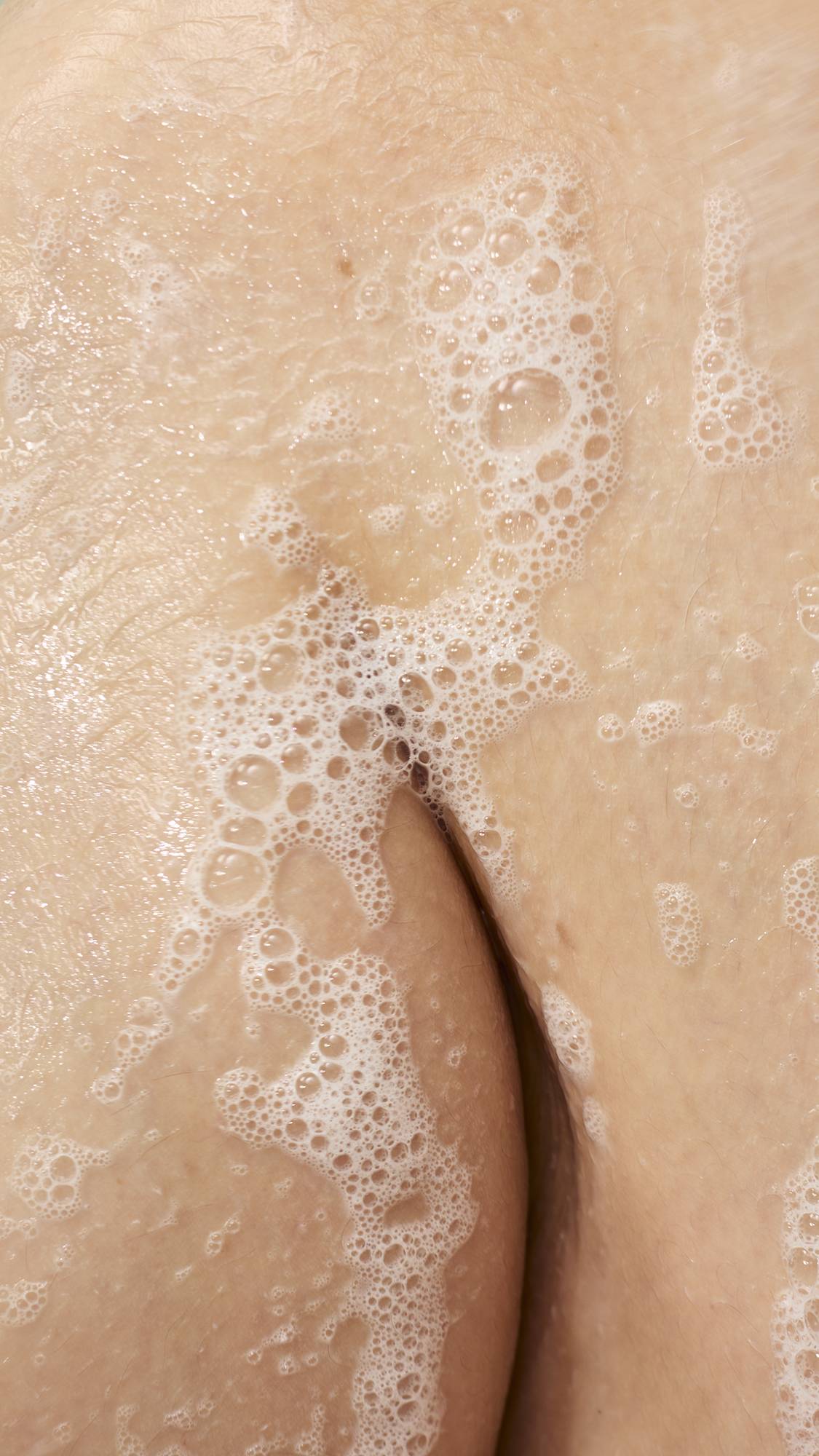 A close-up view captures the delicate, white bubbly lather created by the "Making Daisy Chains" soap on wet skin. The soft foam clings gently to the body, demonstrating the product's cleansing texture.