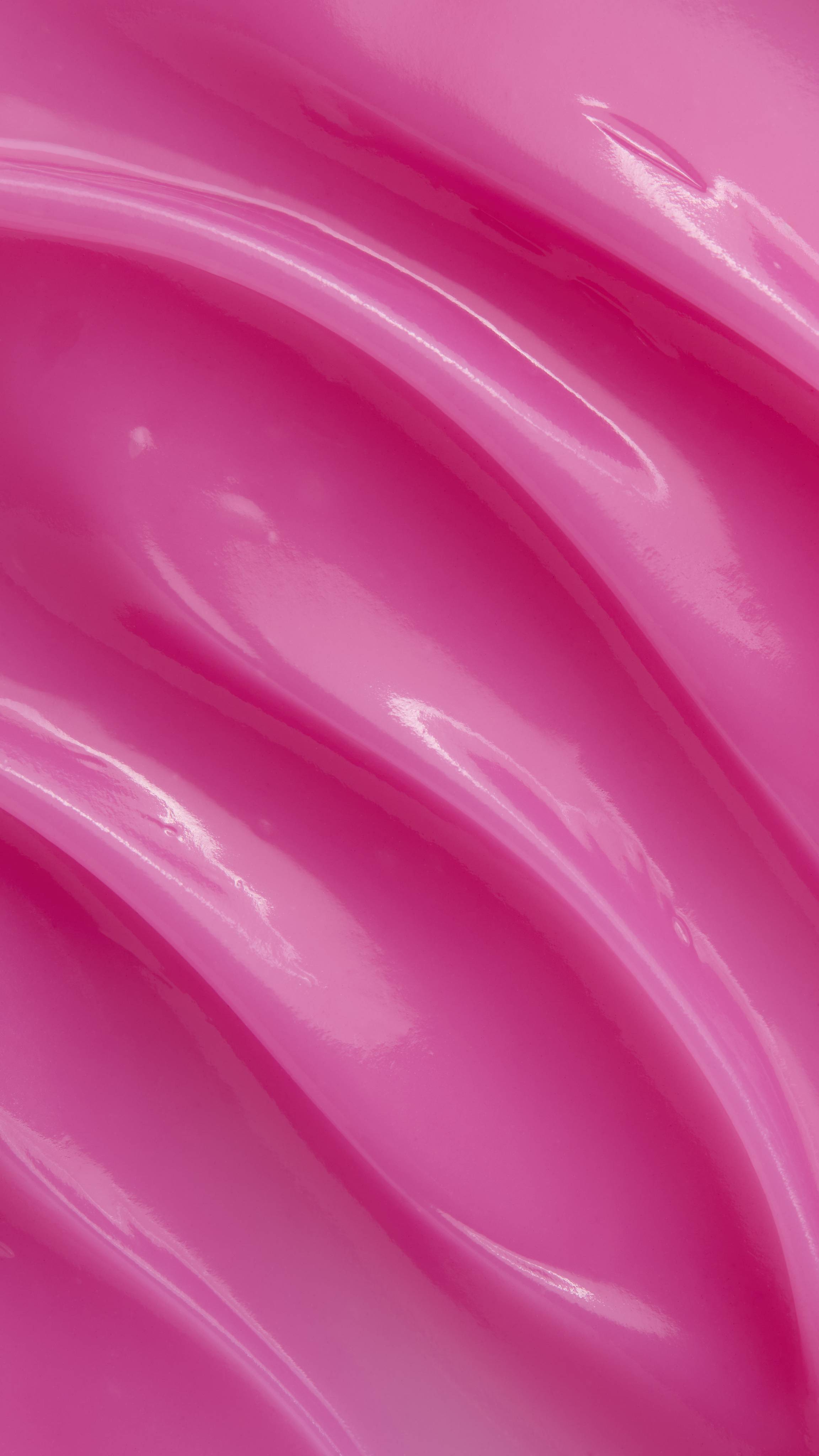 A macro close-up texture shot of vibrant, smooth pink jelly lip mask spread in glossy, thick diagonal waves across the frame.
