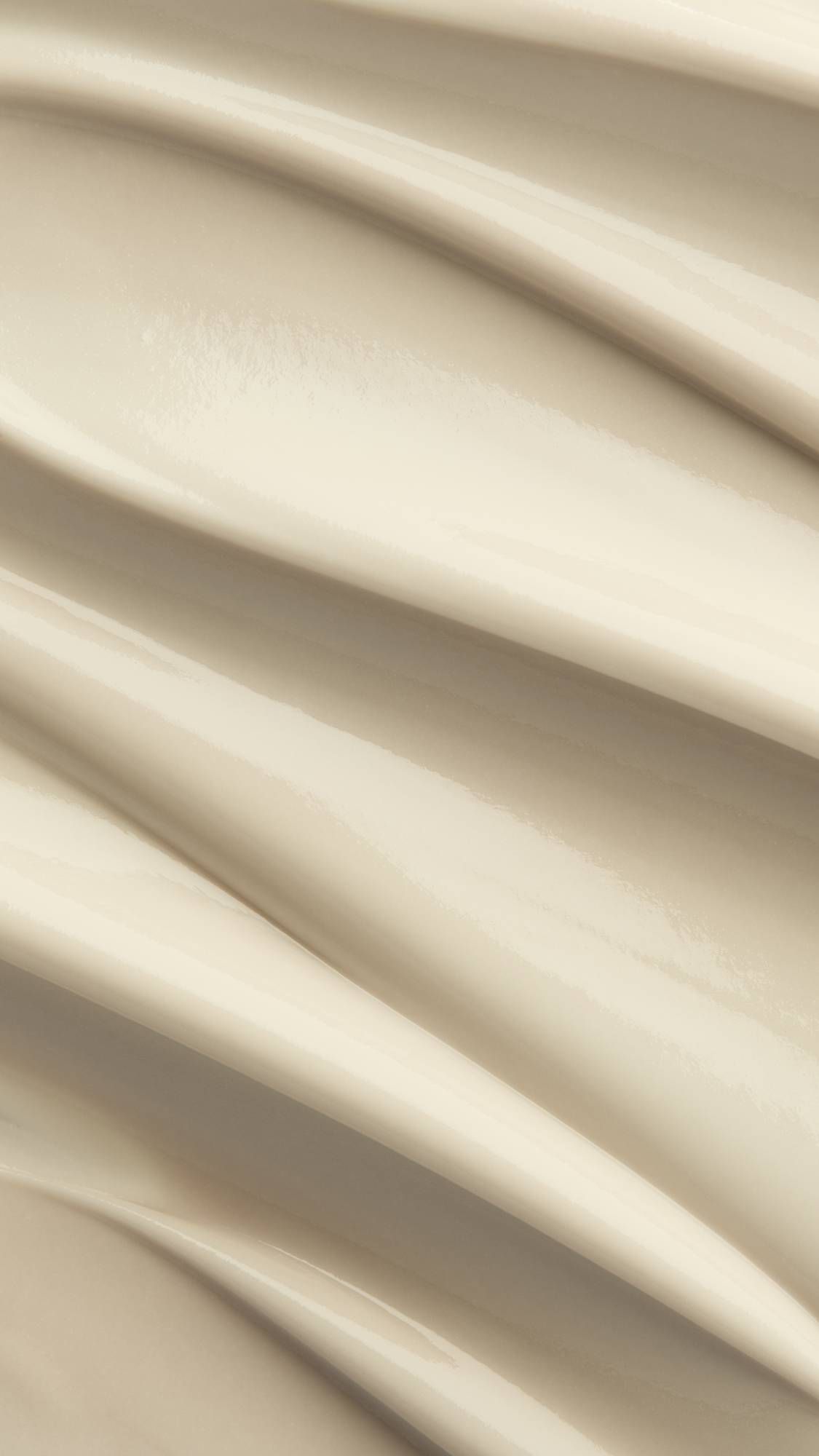 A macro close-up texture shot of rich, cream-coloured Lush "Yuzu Cheesecake" body butter spread in smooth, glossy diagonal waves across the frame.