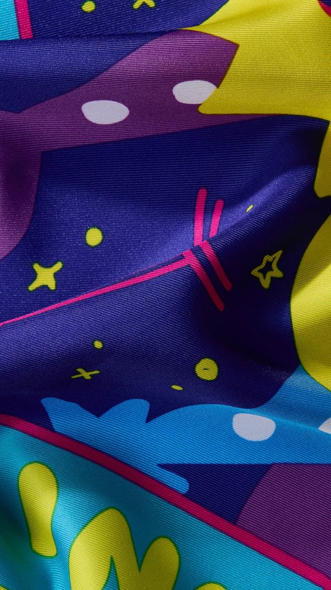 A super close-up image of the Gemini knot wrap to focus on the vibrant contrasting colours and the texture of the fabric. The area focused on has a section of dark, starry sky and a fraction of colourful border. 