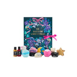 12 Days Of Christmas. A large gift box designed with a dark teal background and a wreath illustration, including holly leaves, partridges, pears, mistletoe and flowers, with gold text, tied with a pink bow. Twelve Lush products sit in front.