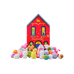 A red brick house-shaped gift box stands behind a large display of festive bath products, including a sleeping fox, a bear, a penguin, and a Christmas tree bath bomb, among many more themed products.