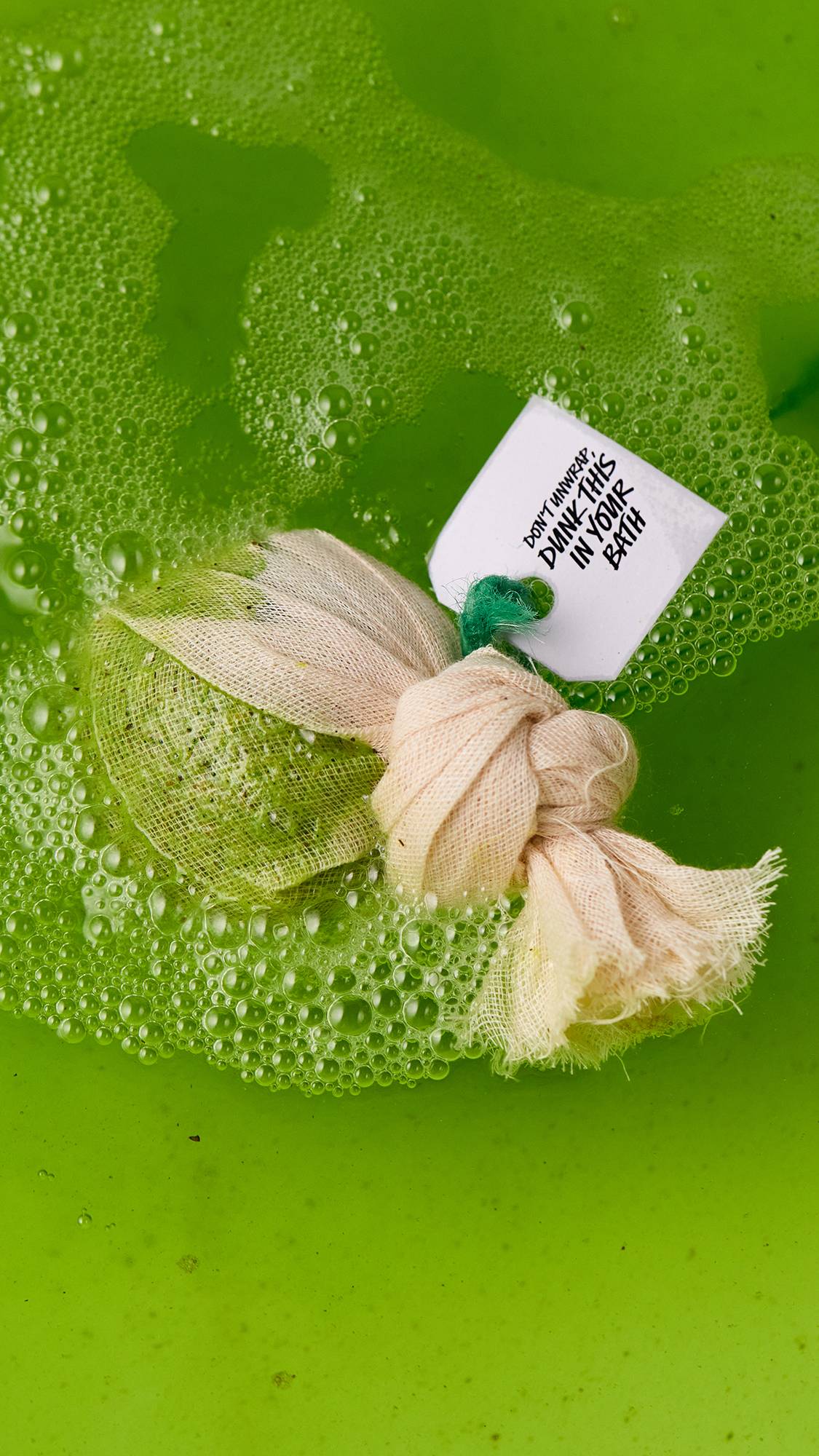 An aerial image of the green Energising Matcha And Peppermint Cataplasm bath bomb as it dissolved in the bath. The water has been turned a vibrant, grass-green colour.