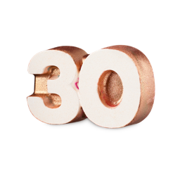 Celebrate 30. A novelty bath bomb shaped like the number "30". The front is a crisp white colour with the edges coated in a shimmering bronze lustre. Flecks of pink and blue are just visible around the edges. 