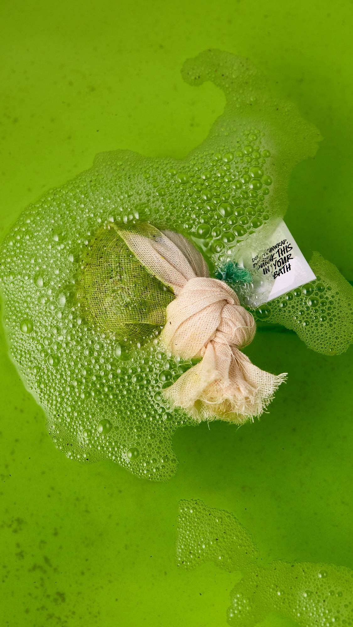 An aerial image of the green Energising Matcha And Peppermint Cataplasm bath bomb as it dissolved in the bath. The water has been turned a vibrant, grass-green colour.