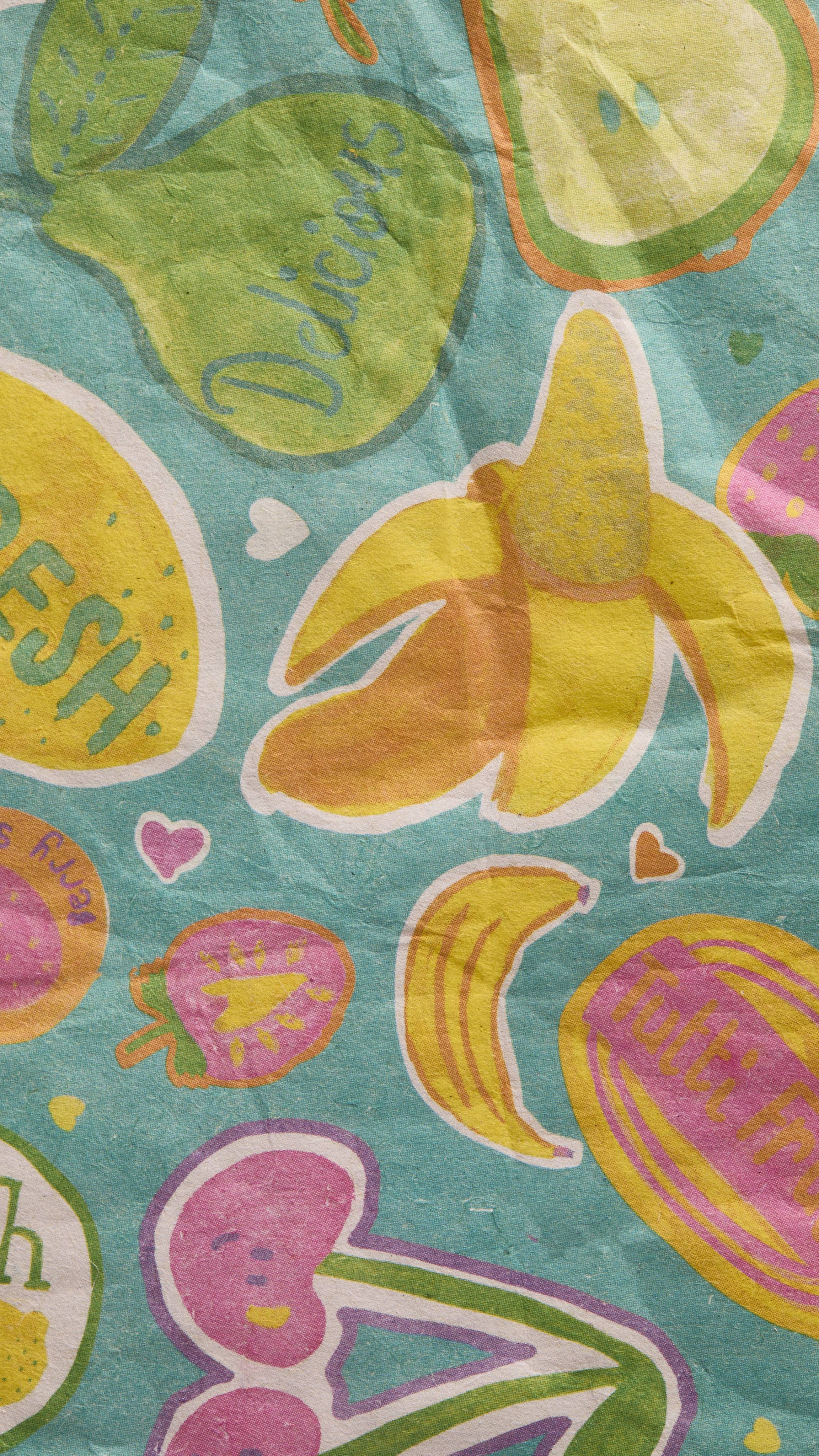 A close-up of the Tutti Frutti Lokta Paper reveals a textured teal background patterned with yellow bananas, green pears, pink cherries, and lemons. Words like "Delicious" and "Fresh" are written on the colourful fruit illustrations.