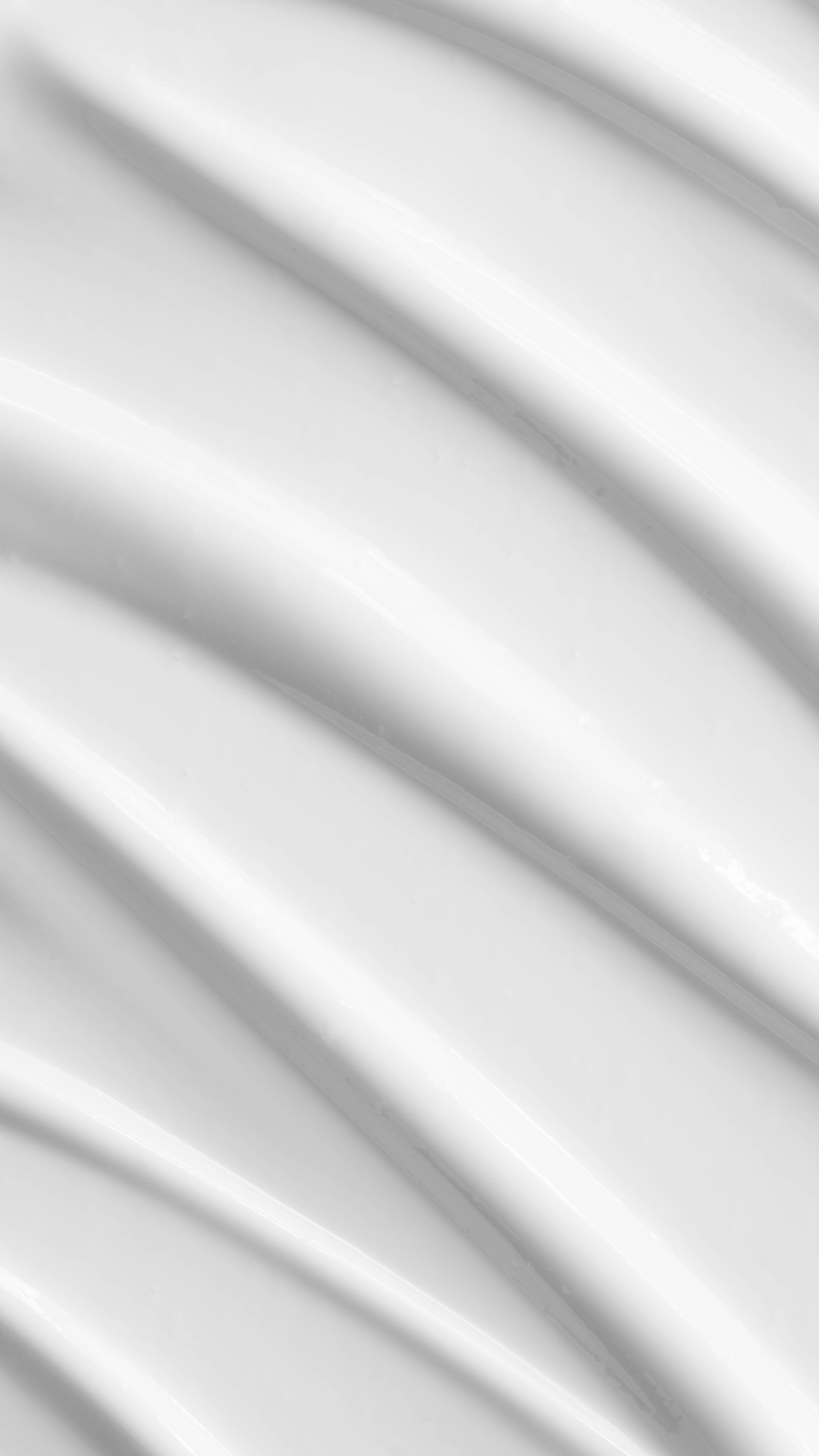 A vertical close-up texture shot highlights the rich consistency of the white 9 to 5 cleanser, styled in smooth, diagonal waves that glisten under the light to showcase the creamy and gentle nature of the product.